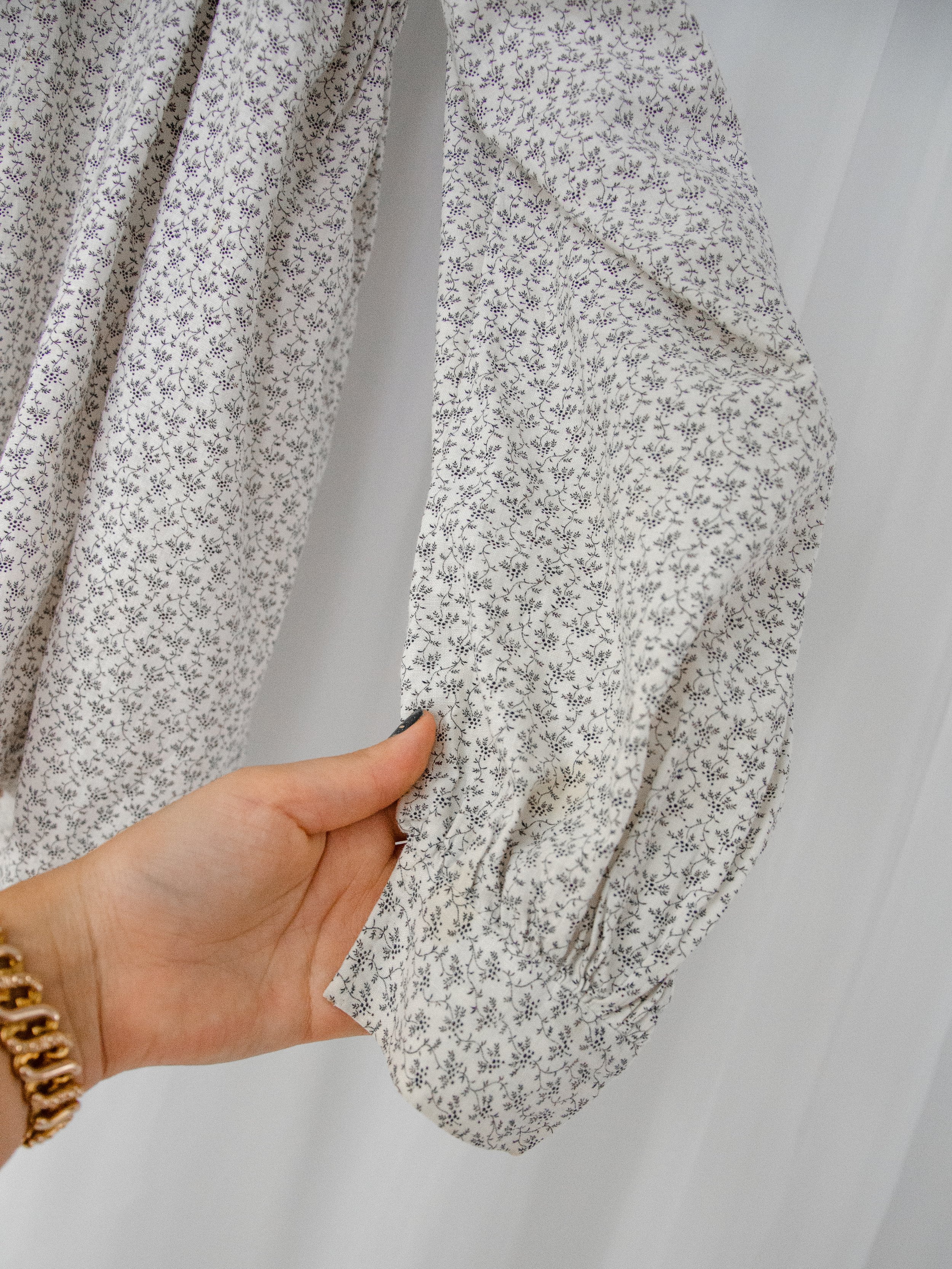 Detail of the Victorian calico top's sleeve held by hand, showing the gathered cuff and small floral print.