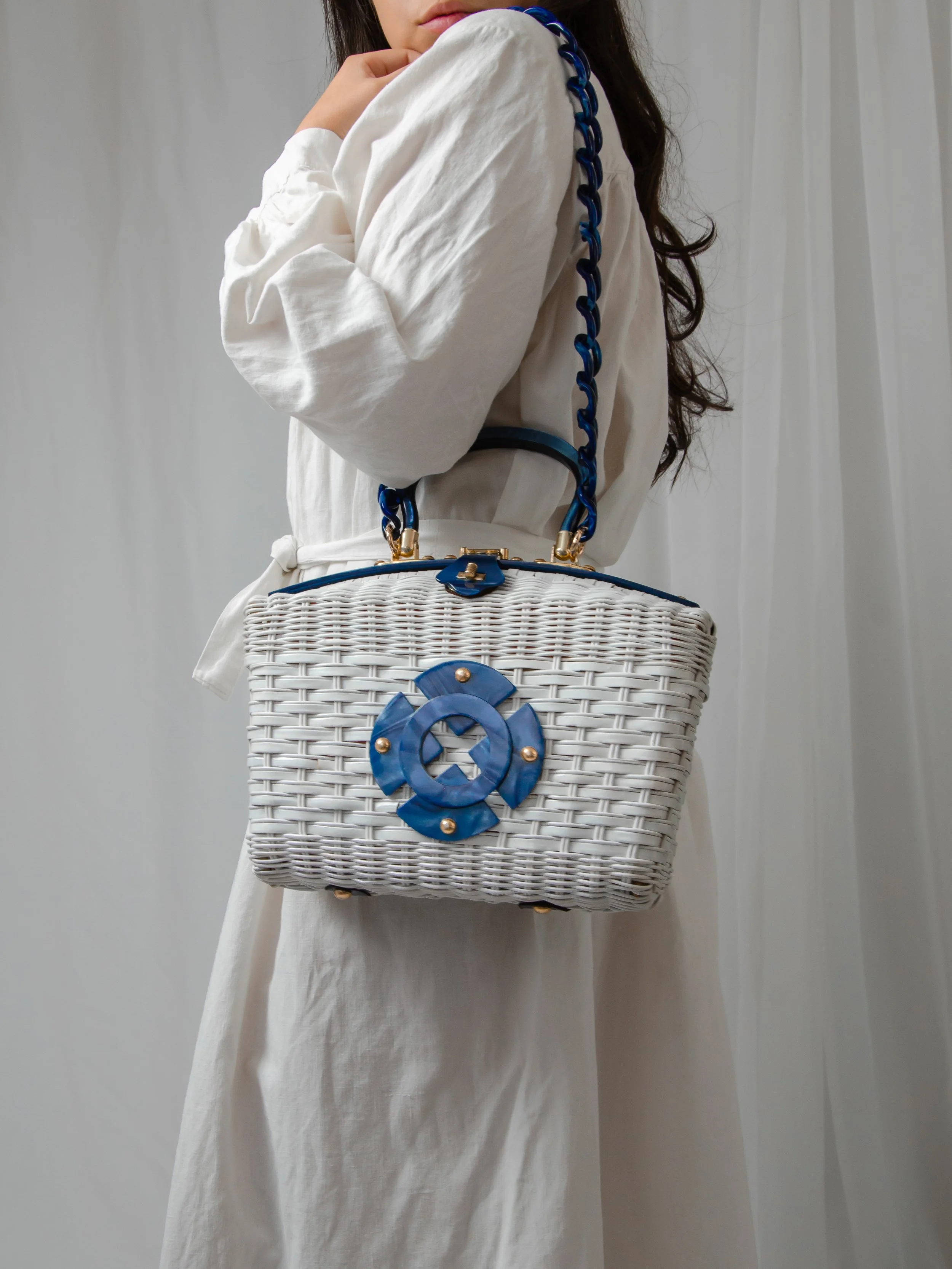 1950s white wicker and marbled blue lucite purse carried on a model's shoulder, side view.