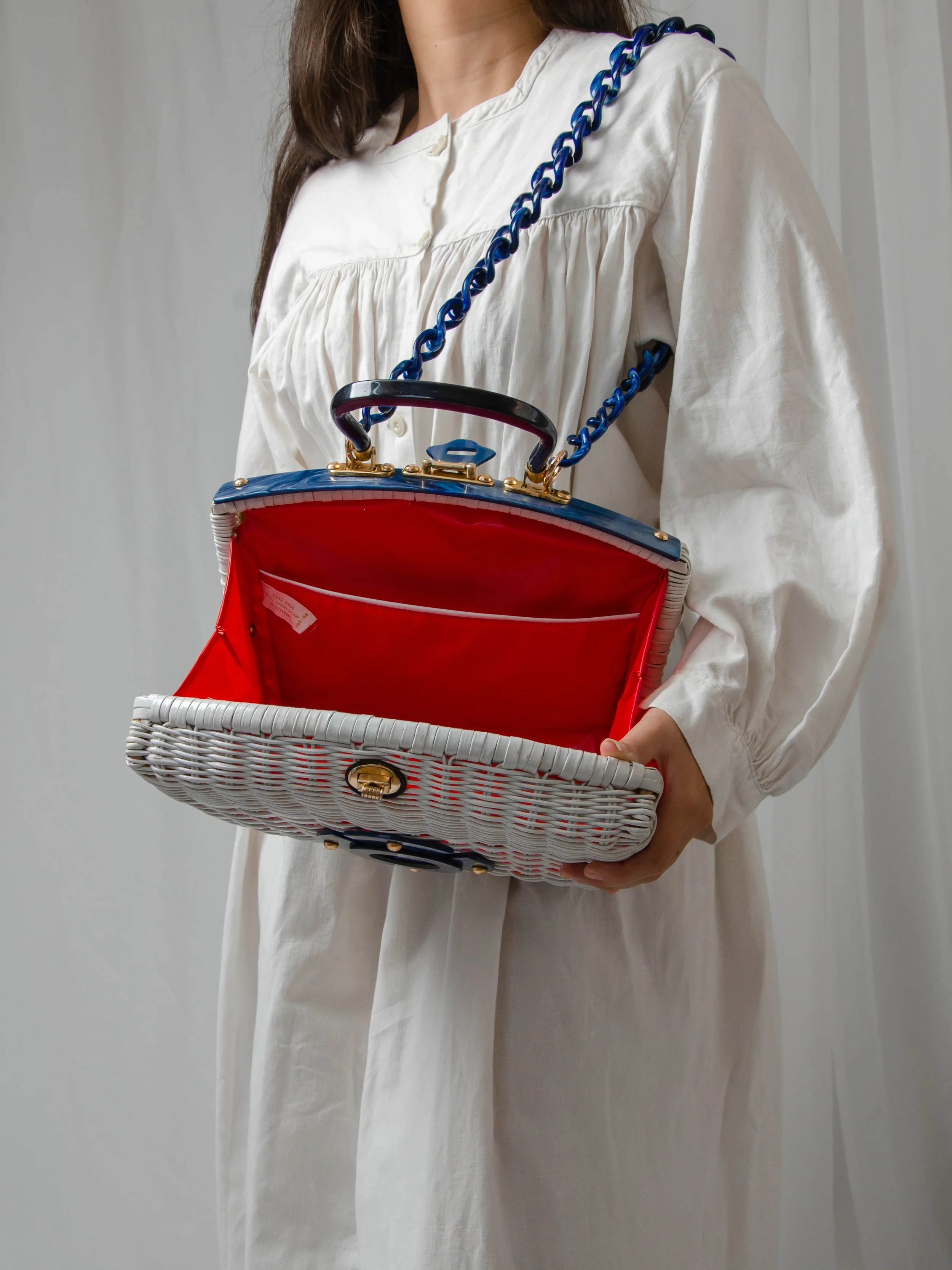 1950s white wicker and blue lucite purse held open on a model, showing the cherry red vinyl lining.