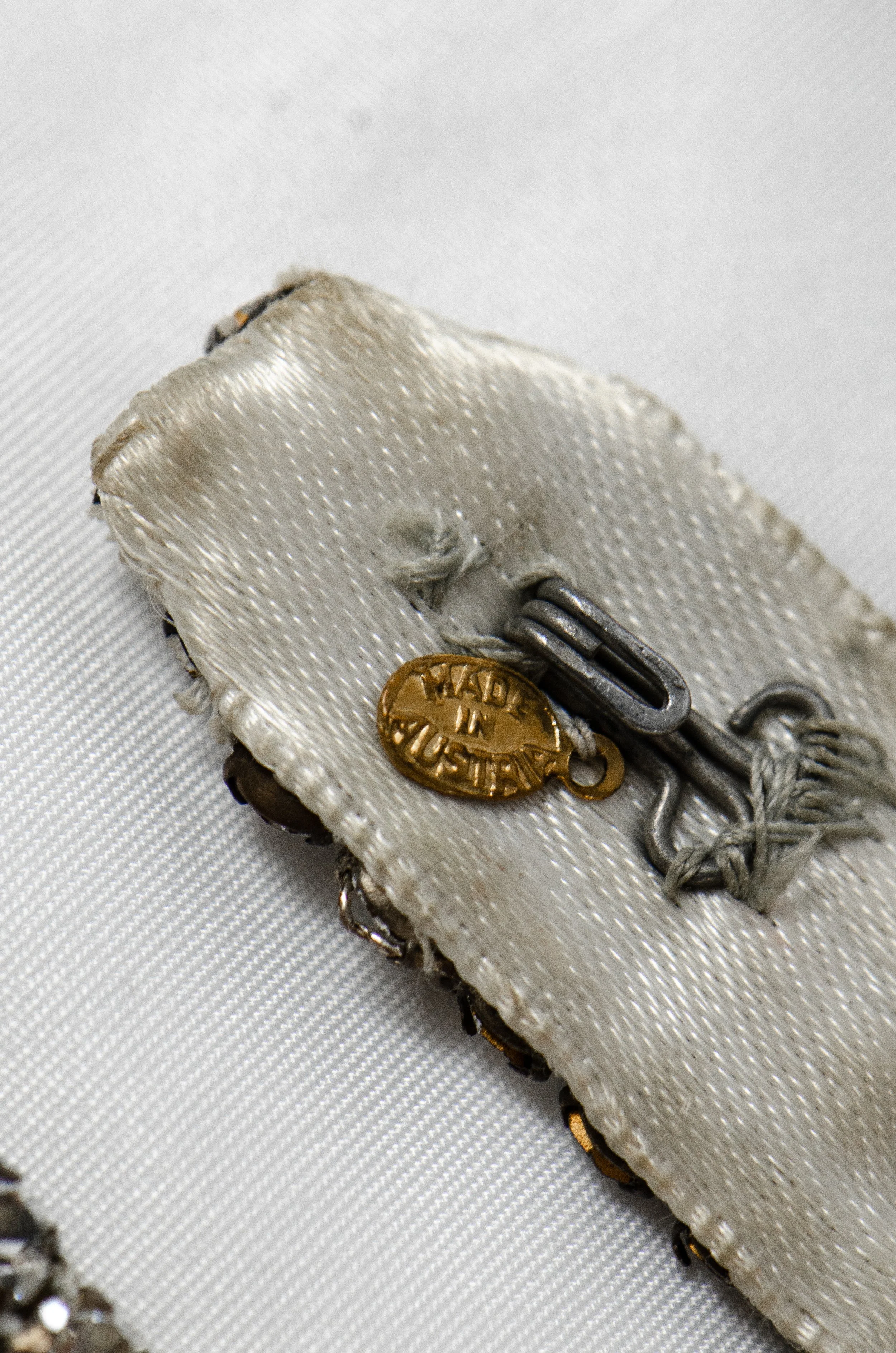 Detail of the 1950s rhinestone belt's satin backing with a 'Made in Austria' tag and hook.
