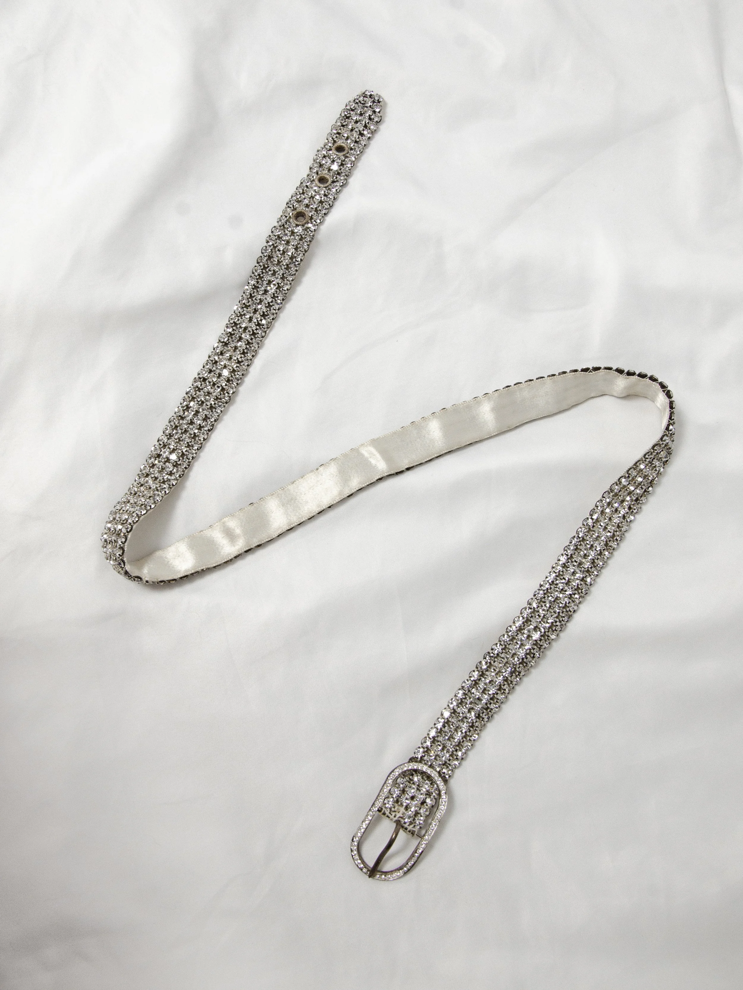 Early 1950s Austrian crystal belt laid flat on white fabric, showing the full length and oval buckle.
