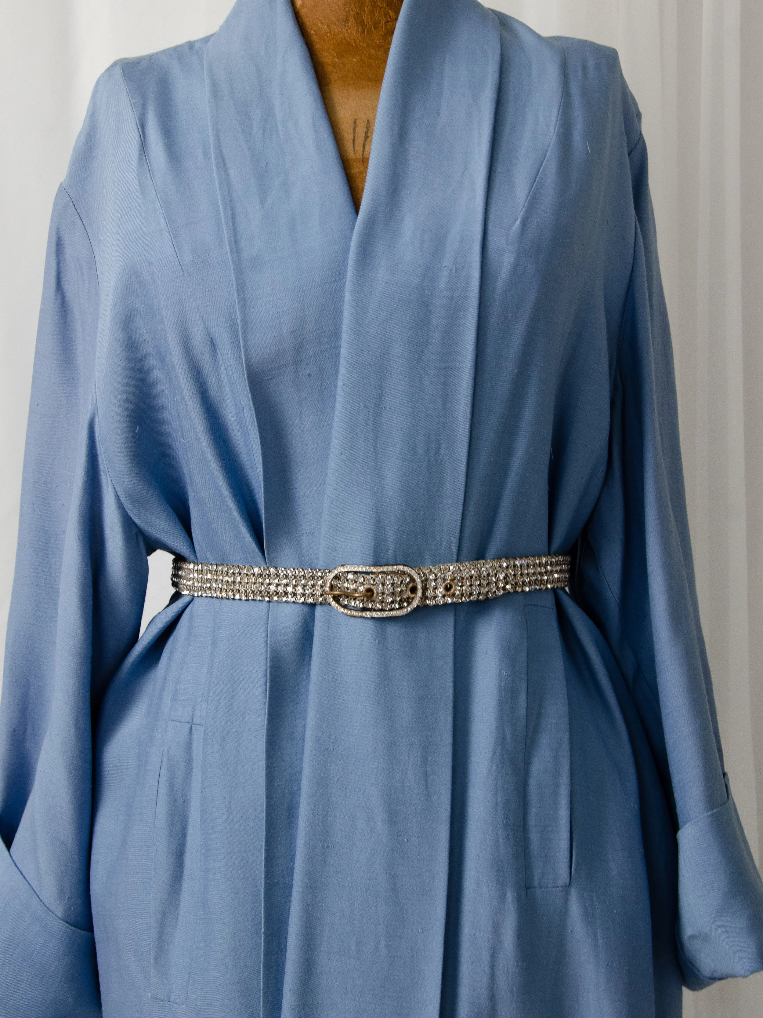 Early 1950s Austrian rhinestone belt cinching a light blue wrap dress on a dress form.