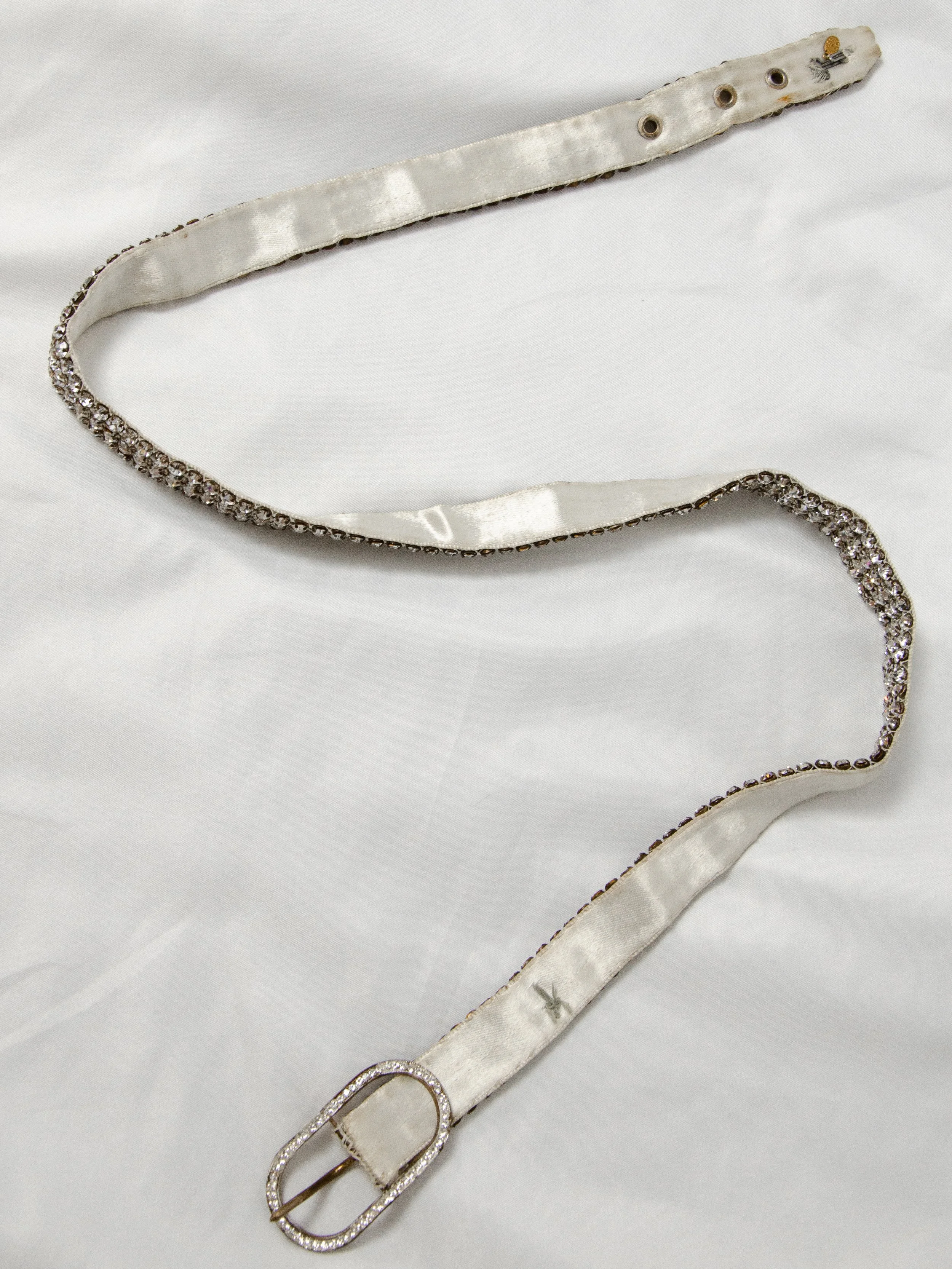 Early 1950s Austrian crystal belt laid flat face down, showing the ivory satin backing.
