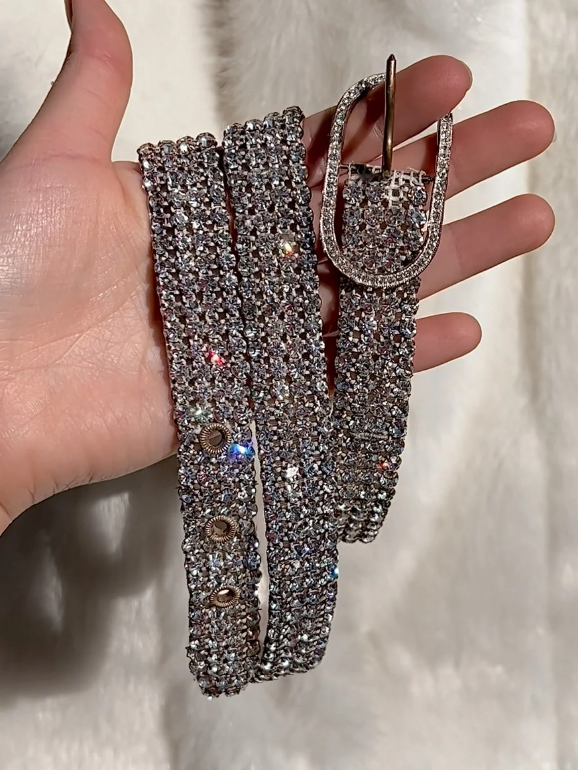 Early 1950s Austrian rhinestone belt held coiled in a hand, showing rows of sparkling crystals.