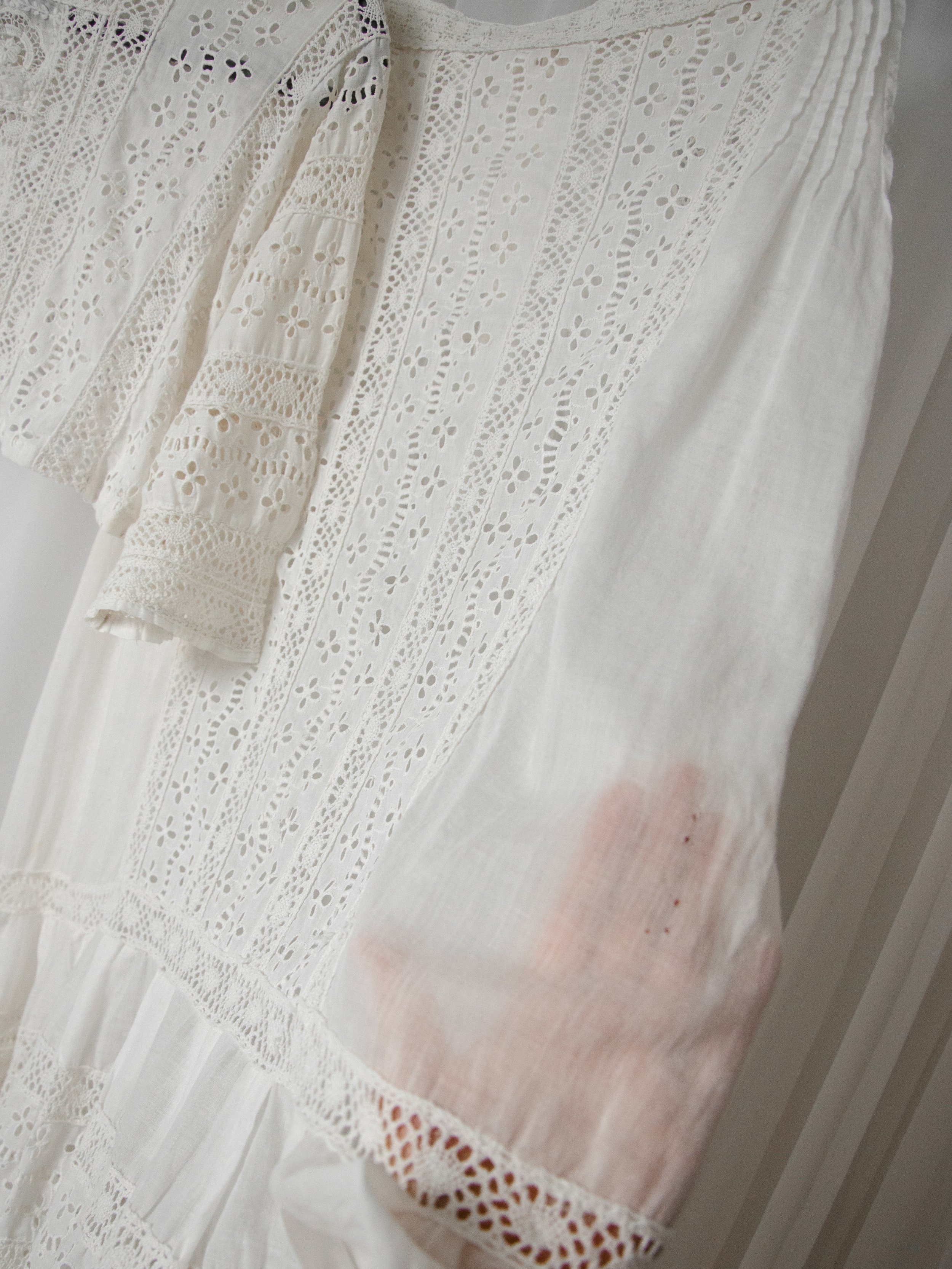 Detail of the Edwardian eyelet skirt with a hand behind the cotton, revealing a spot of small pinholes.