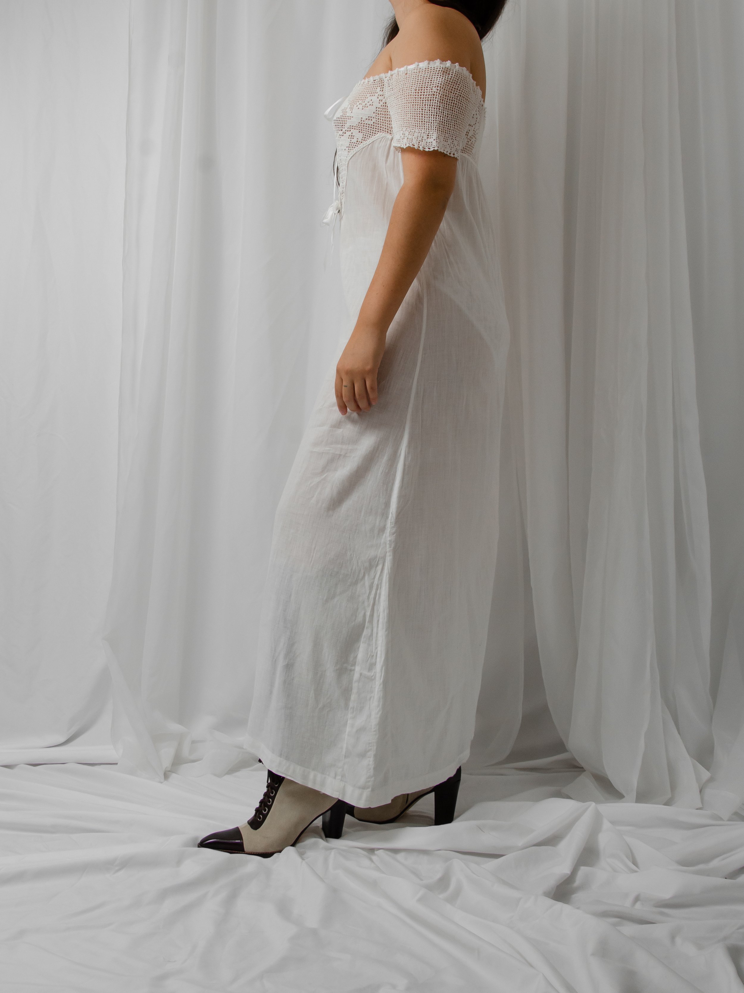 Side view of the antique white off-shoulder dress on a model, showing the long straight skirt.