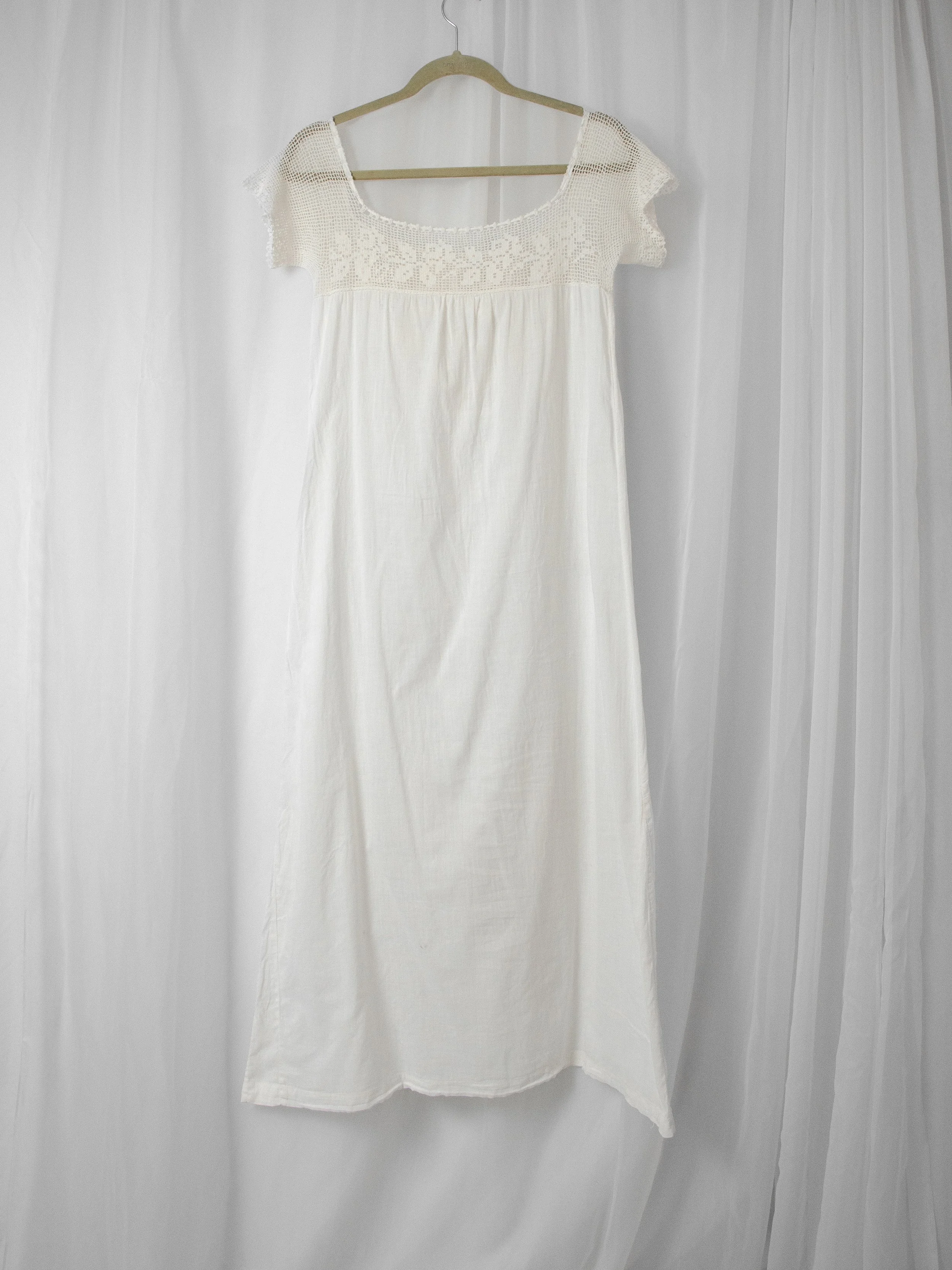 Edwardian white cotton off-shoulder dress on a hanger, full-length front view.