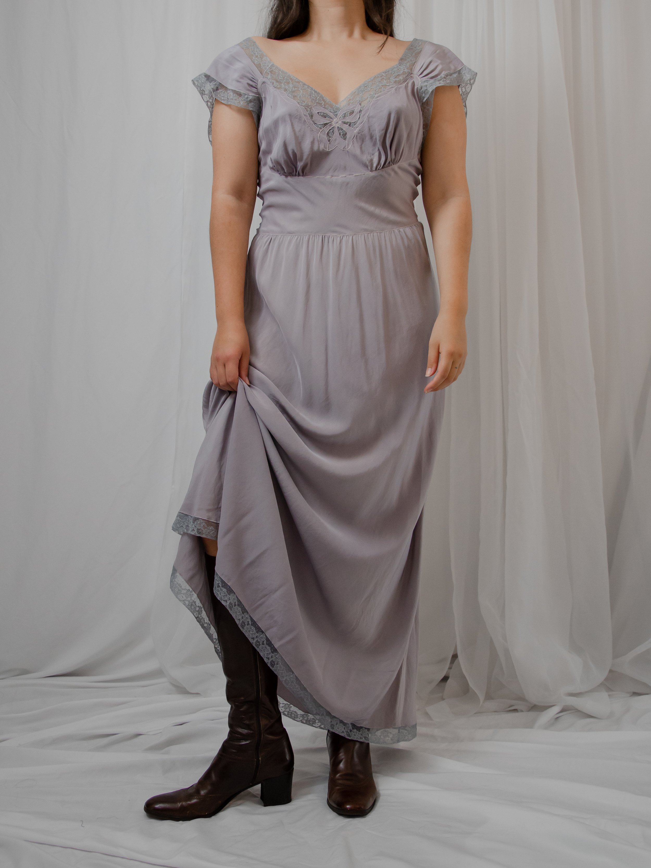 1940s dusty lavender silk dress with lace trims, worn on a model lifting the skirt over brown boots.