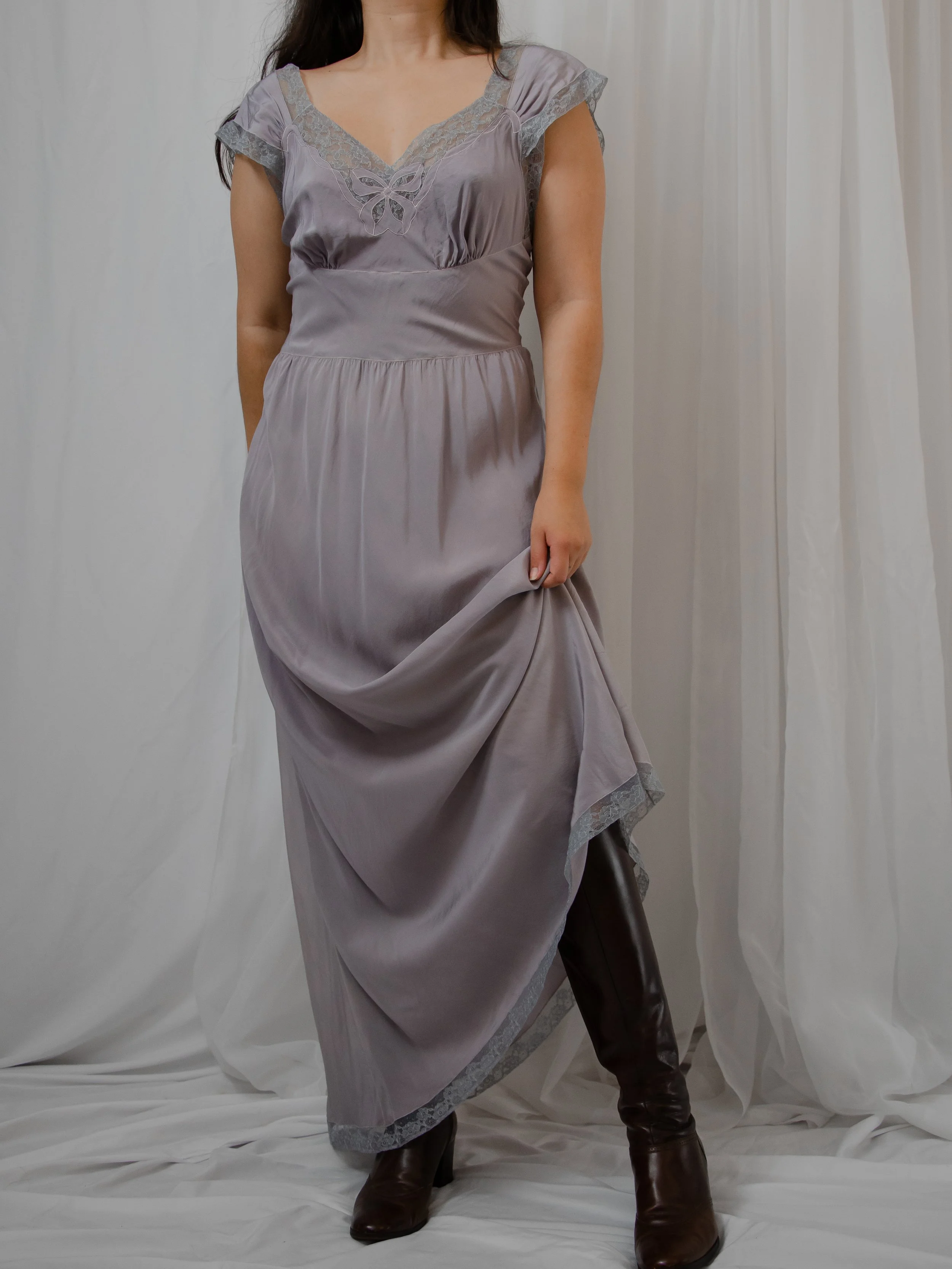 1940s lavender silk dress on a model holding up the skirt to show the lace-edged hem.