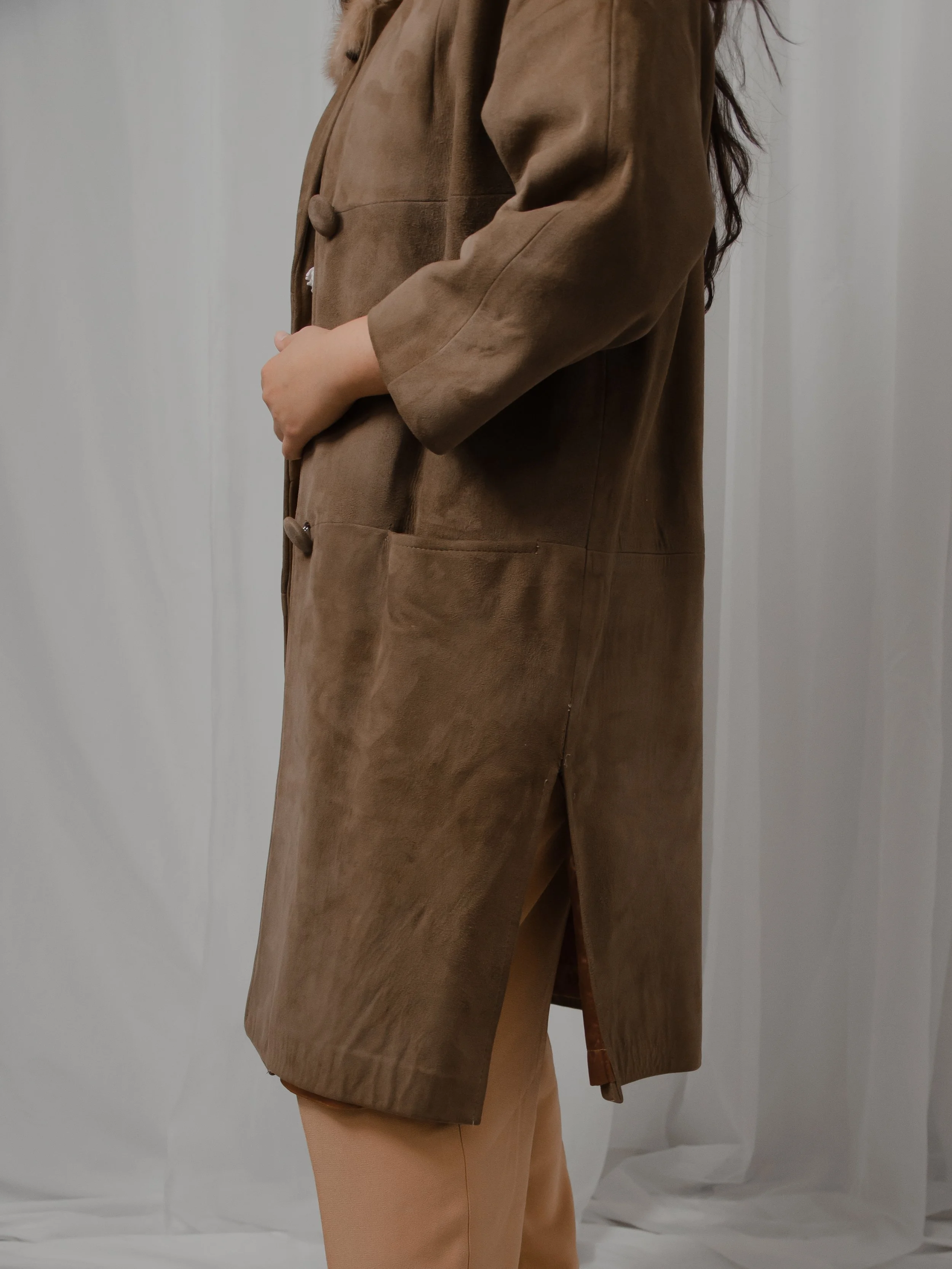 Side detail of the 1940s brown suede coat on a model, showing the pocket, covered buttons and side vent.