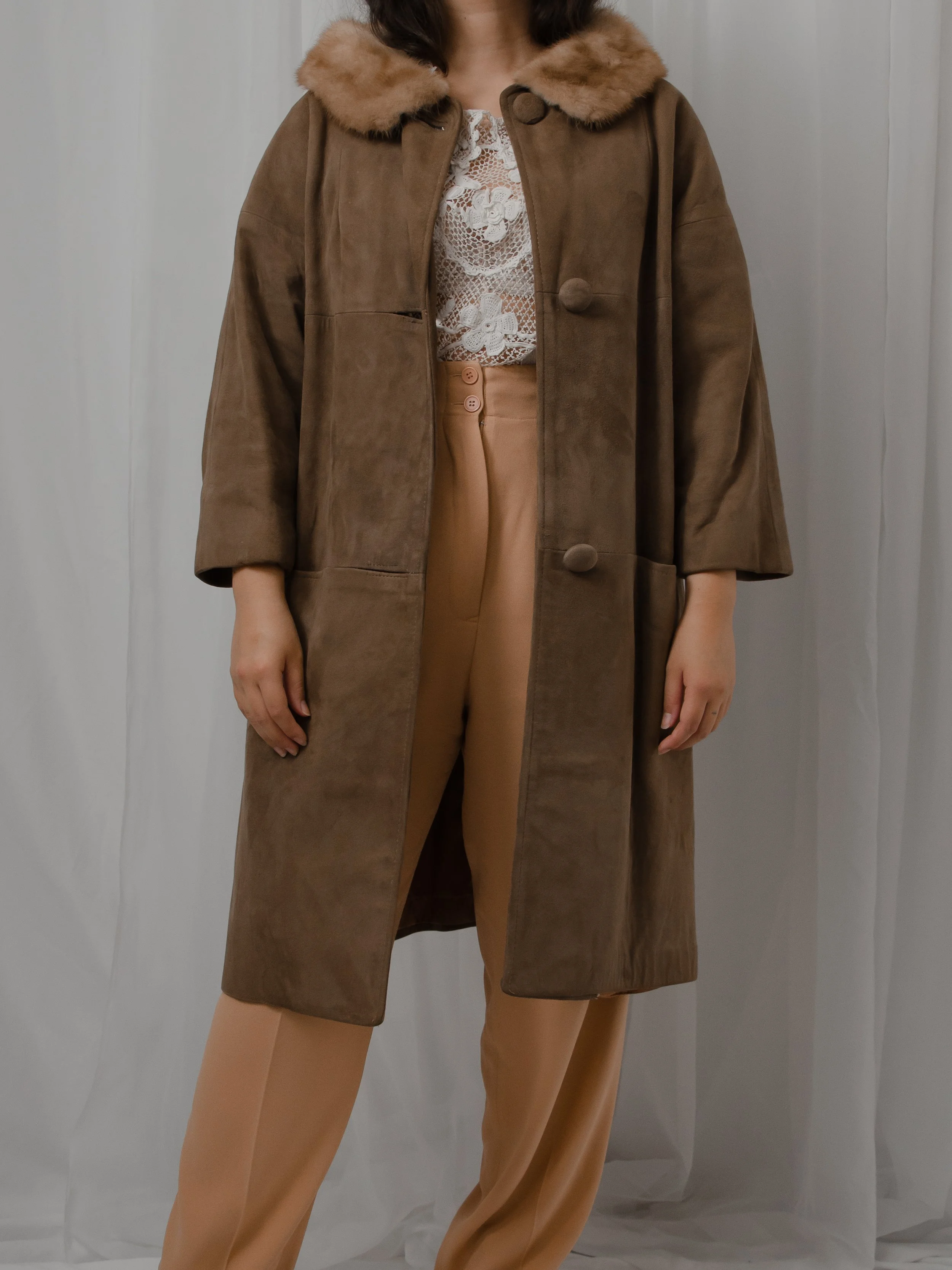 Front view of the 1940s suede and mink coat worn open on a model over a lace top.