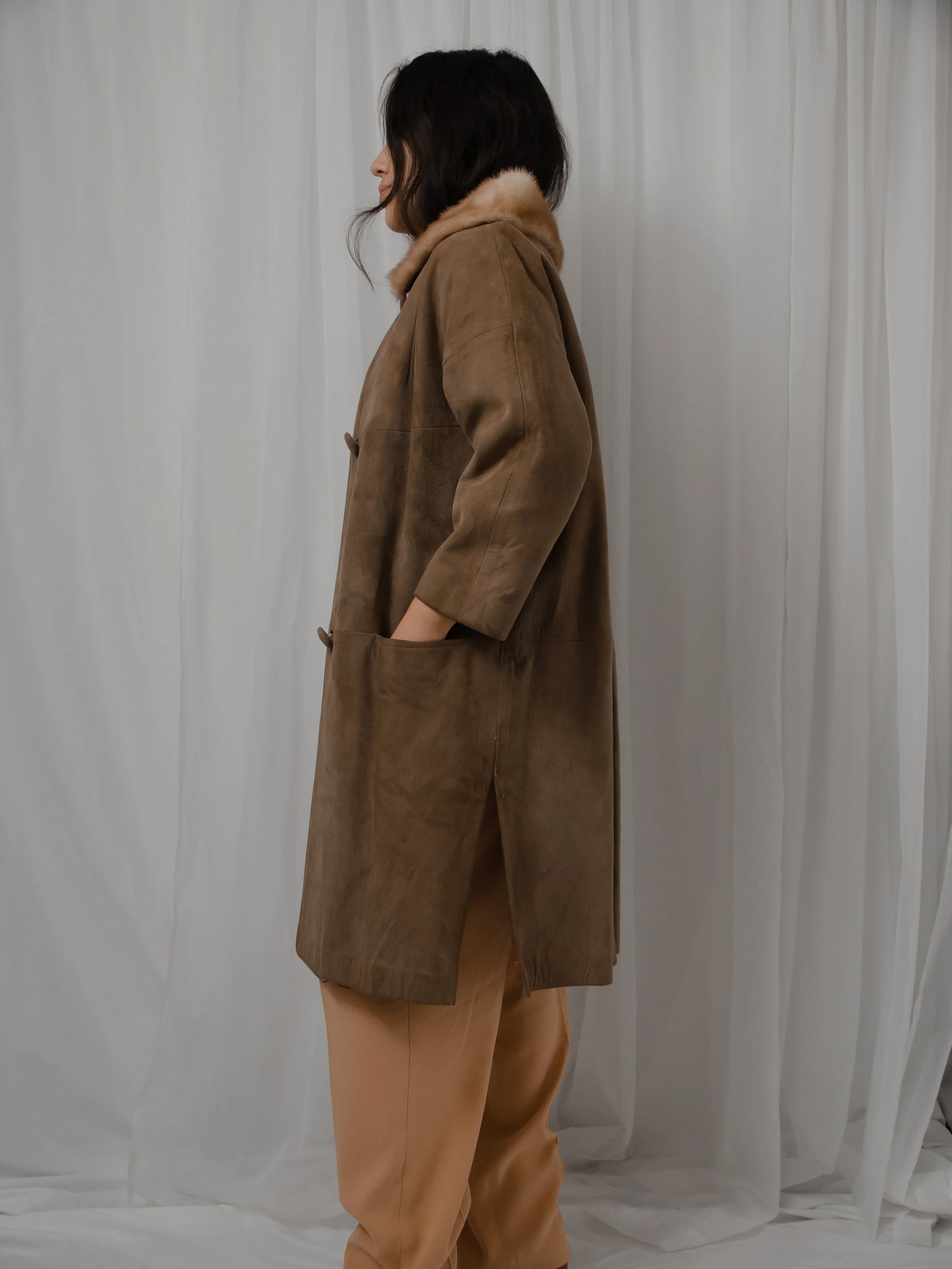 Side view of the 1940s brown suede coat on a model, showing the cropped sleeve and side slit.