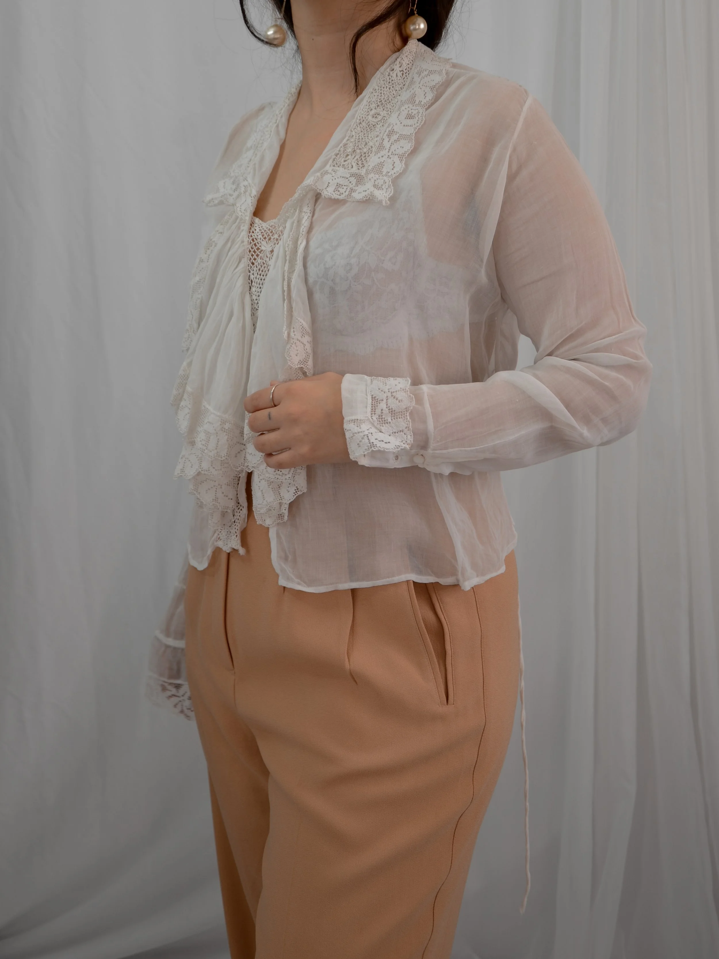 Three-quarter view of the 1910s sheer white ruffle blouse on a model, showing lace cuffs.
