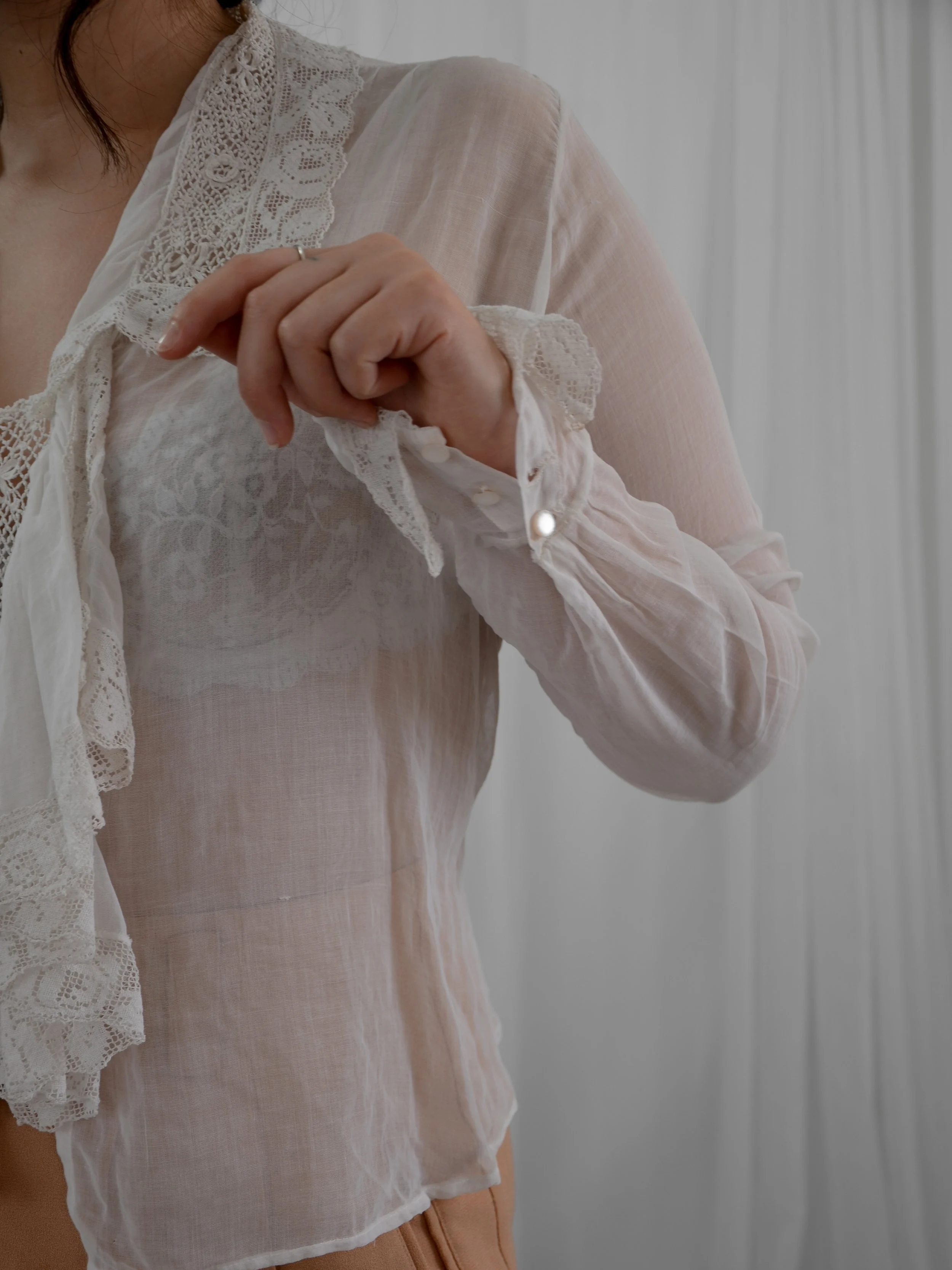 Detail of the late Edwardian ruffle blouse's sheer sleeve with lace cuff and button.