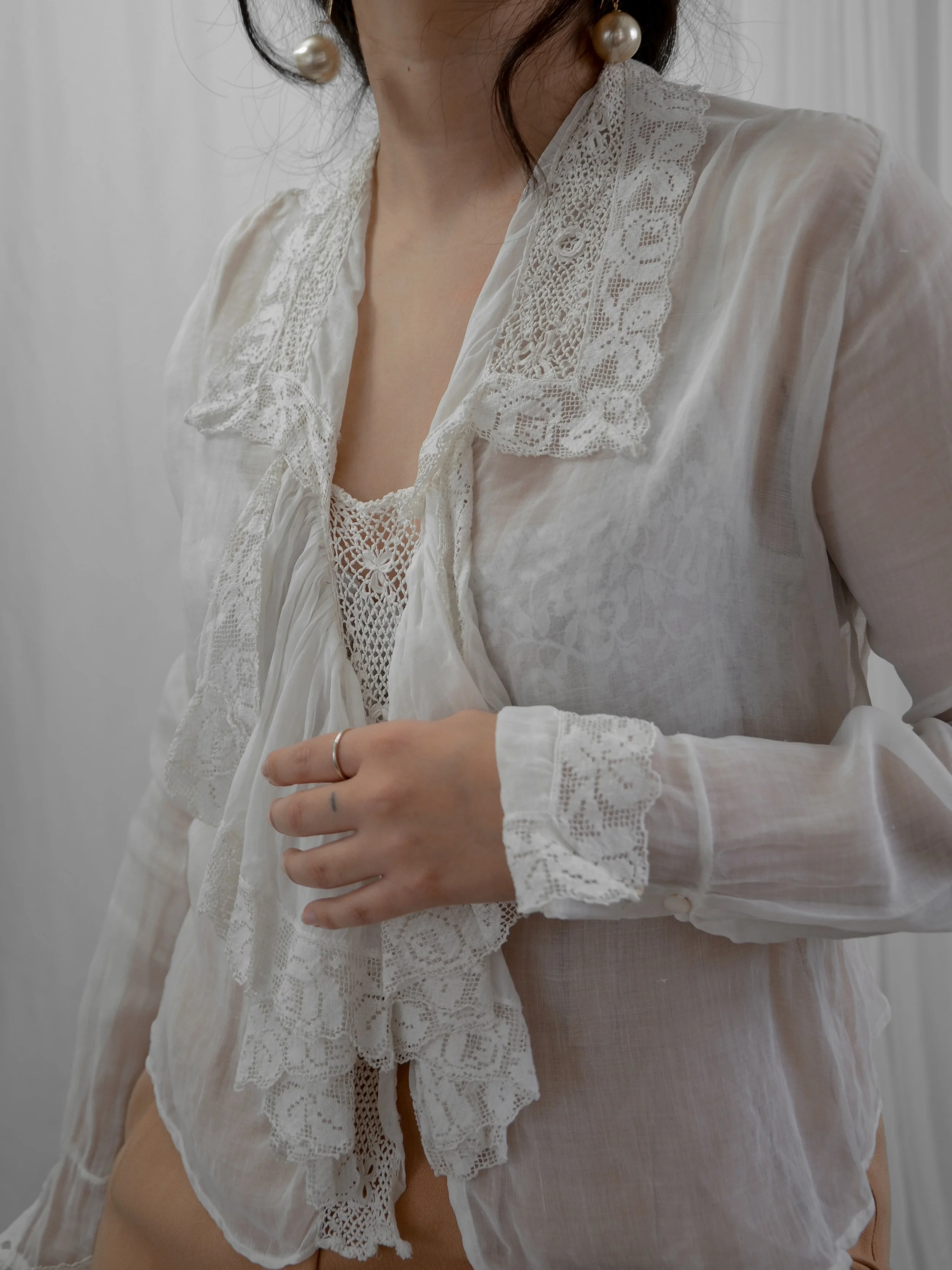 Front view of the 1910s sheer white cotton blouse on a model, showing the lace-edged cascading ruffle.