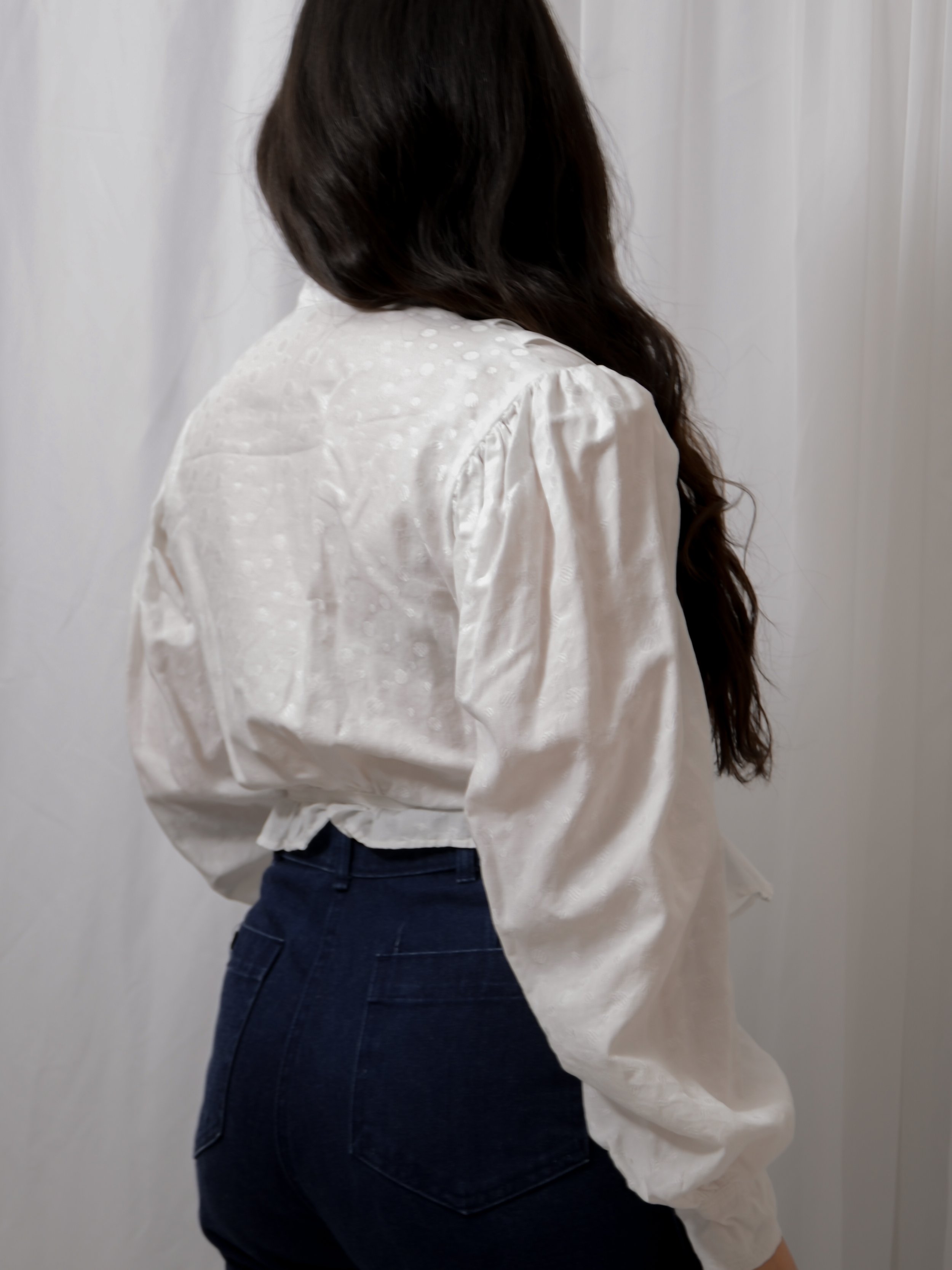 Back view of the Edwardian white cotton dot blouse on a model, showing the puffed shoulders.