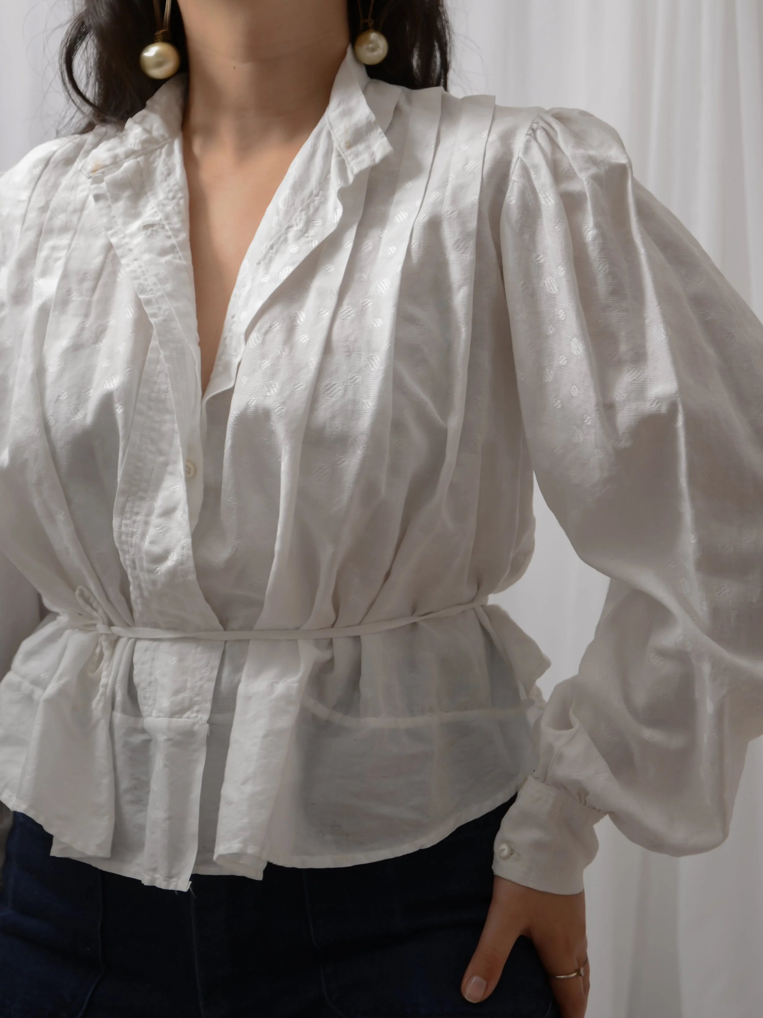 Close-up of the Edwardian white dot blouse front, showing the open collar, pleats and cinched waist tie.