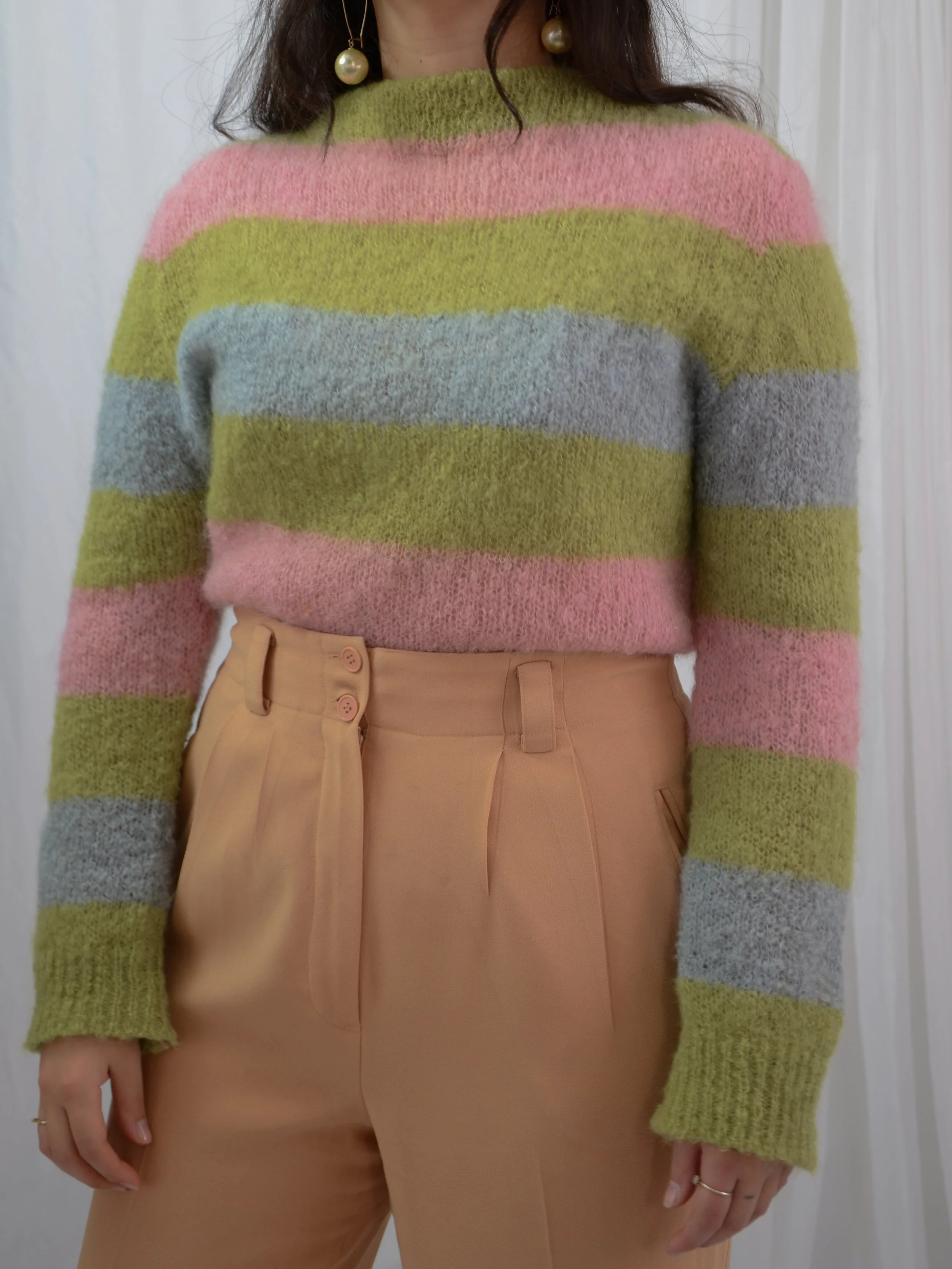 Front view of the 1960s striped color block jumper tucked into tan high-waisted trousers.