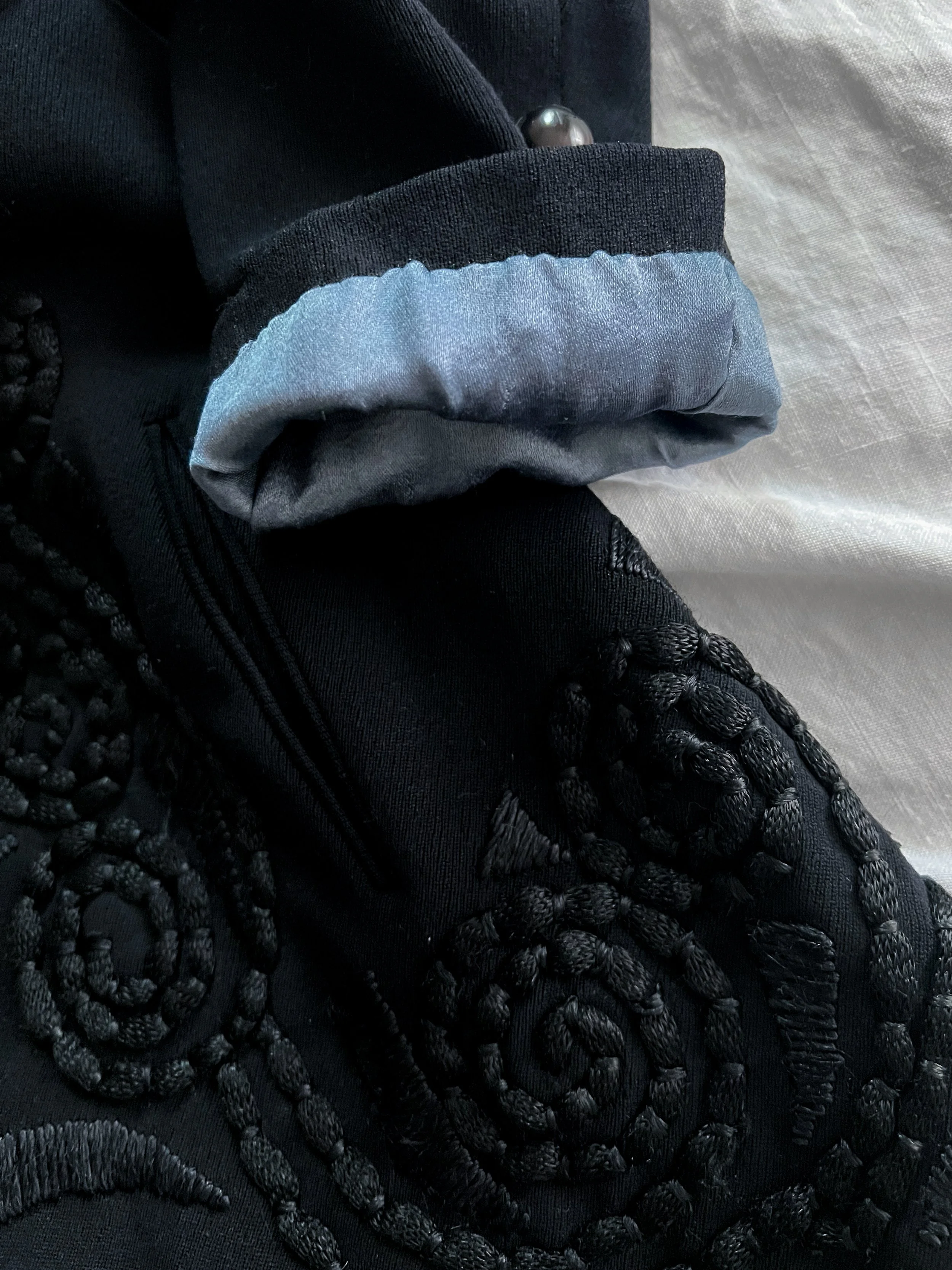 Close-up of the Edwardian jacket's satin swirl embroidery and turned-back cuff with pale blue silk lining.