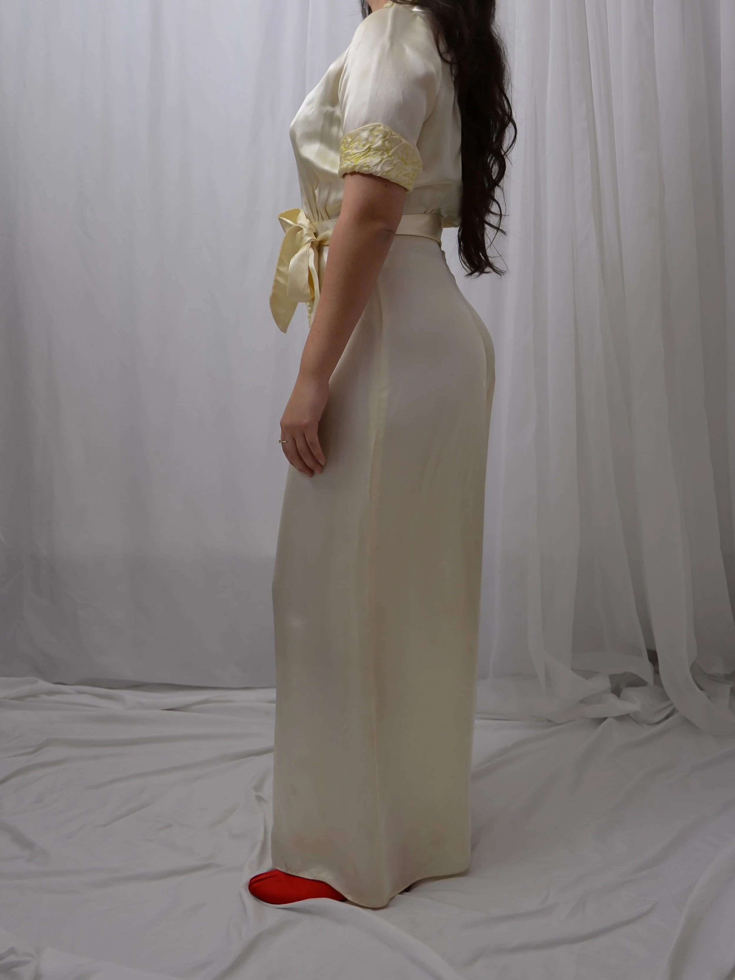 Side view of the 1940s buttercream satin jumpsuit on a model, showing the full wide-leg pants.