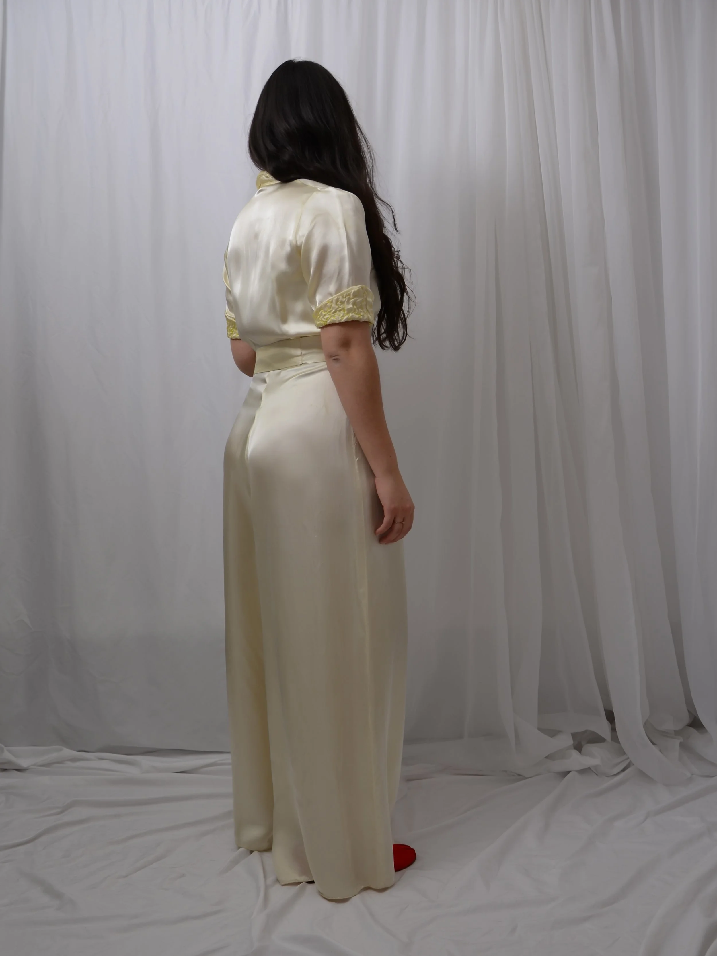 Back view of the 1940s satin wide-leg jumpsuit on a model, showing the puff sleeves and sash.