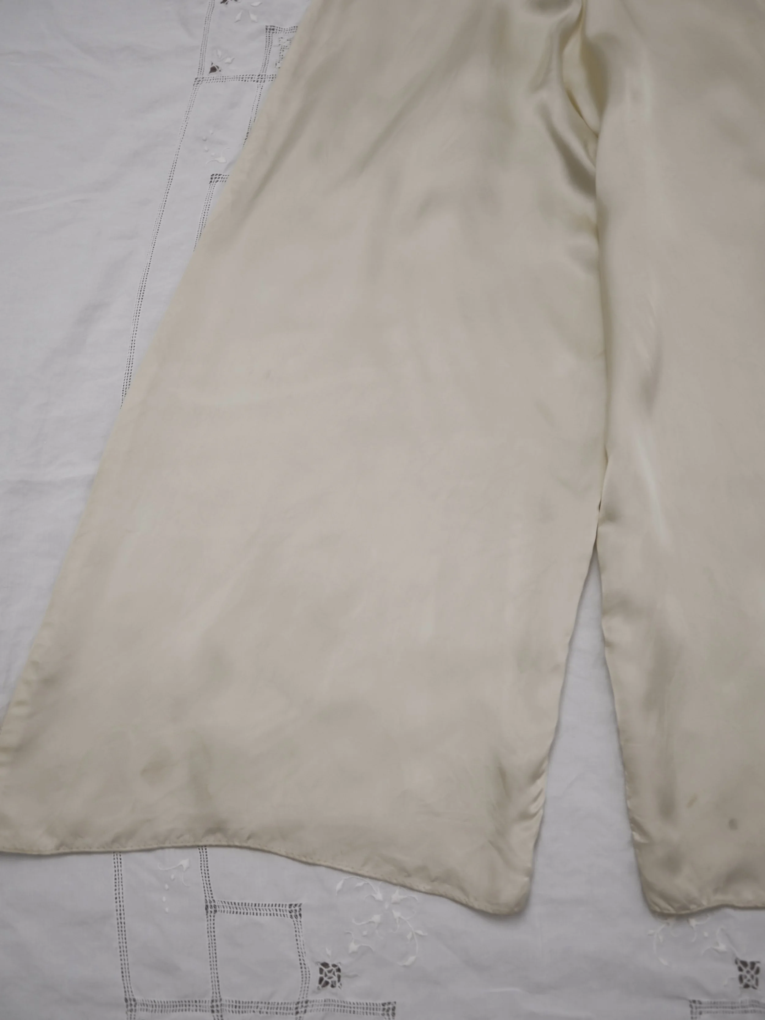 1940s buttercream satin jumpsuit pant legs laid flat, showing faint marks near the hems.