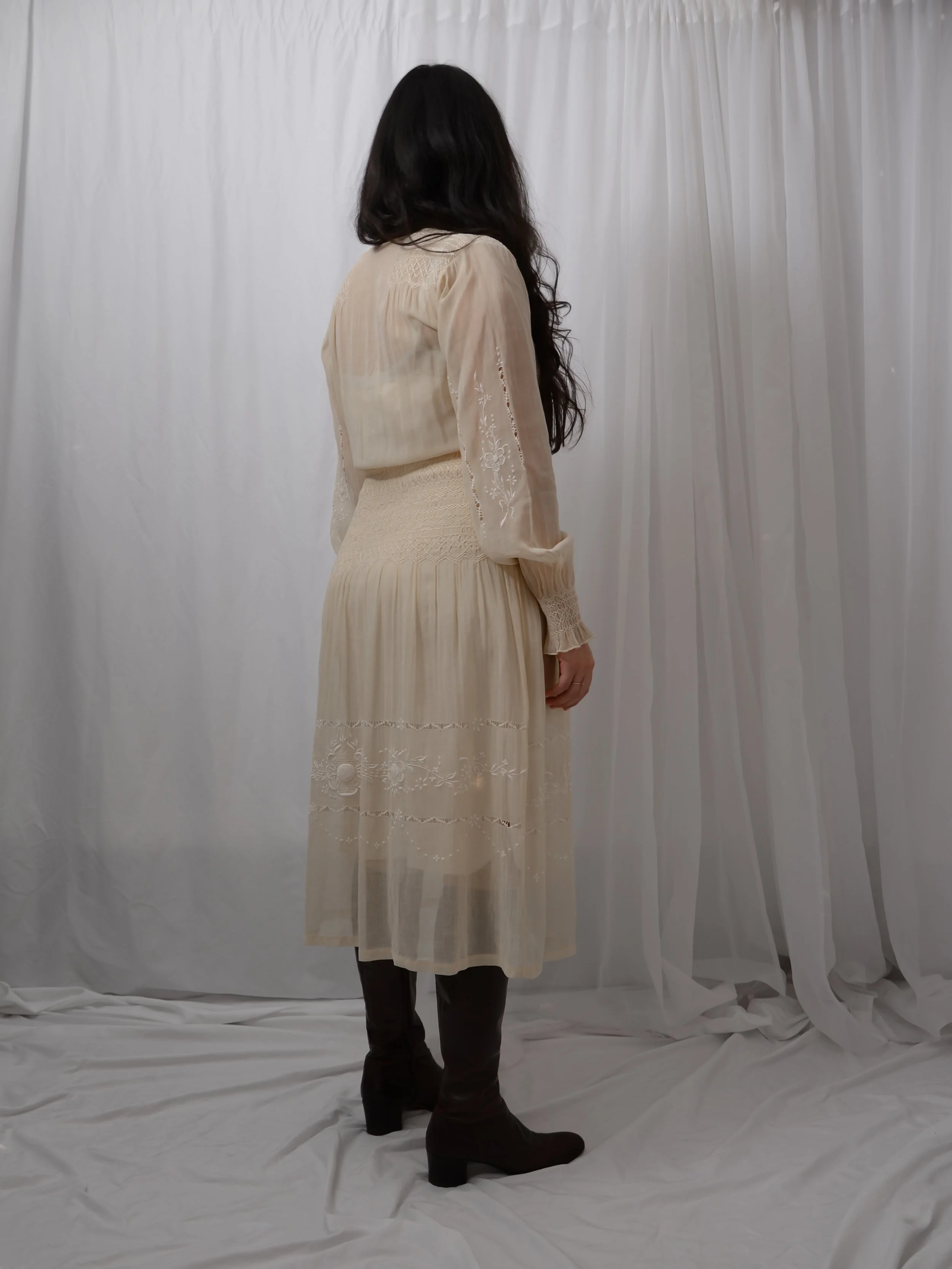 Back view of the 1920s Hungarian smocked dress on a model, showing the long sleeves and midi skirt.