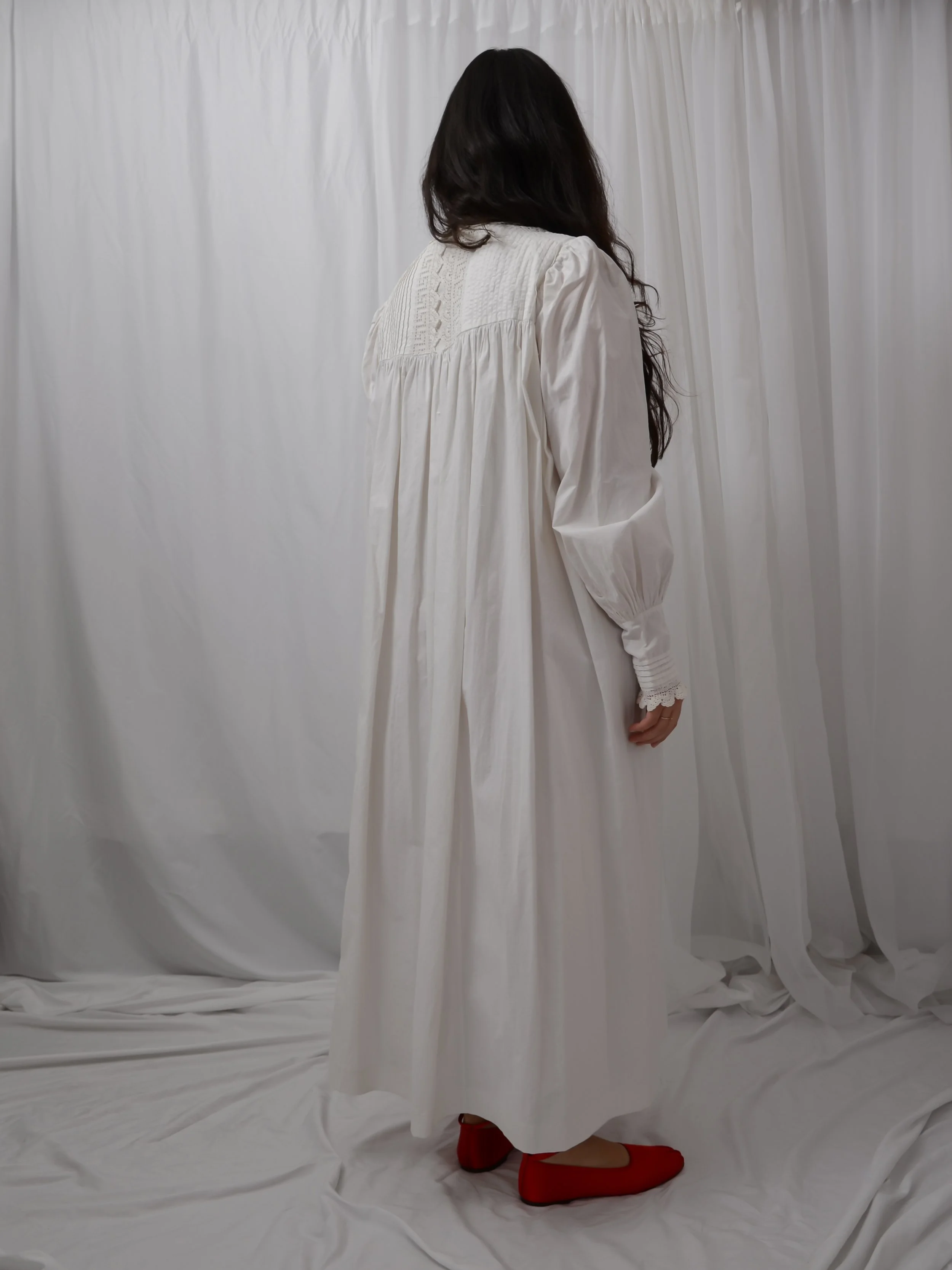 Back view of the antique white cotton button-down dress on a model, showing the gathered yoke.