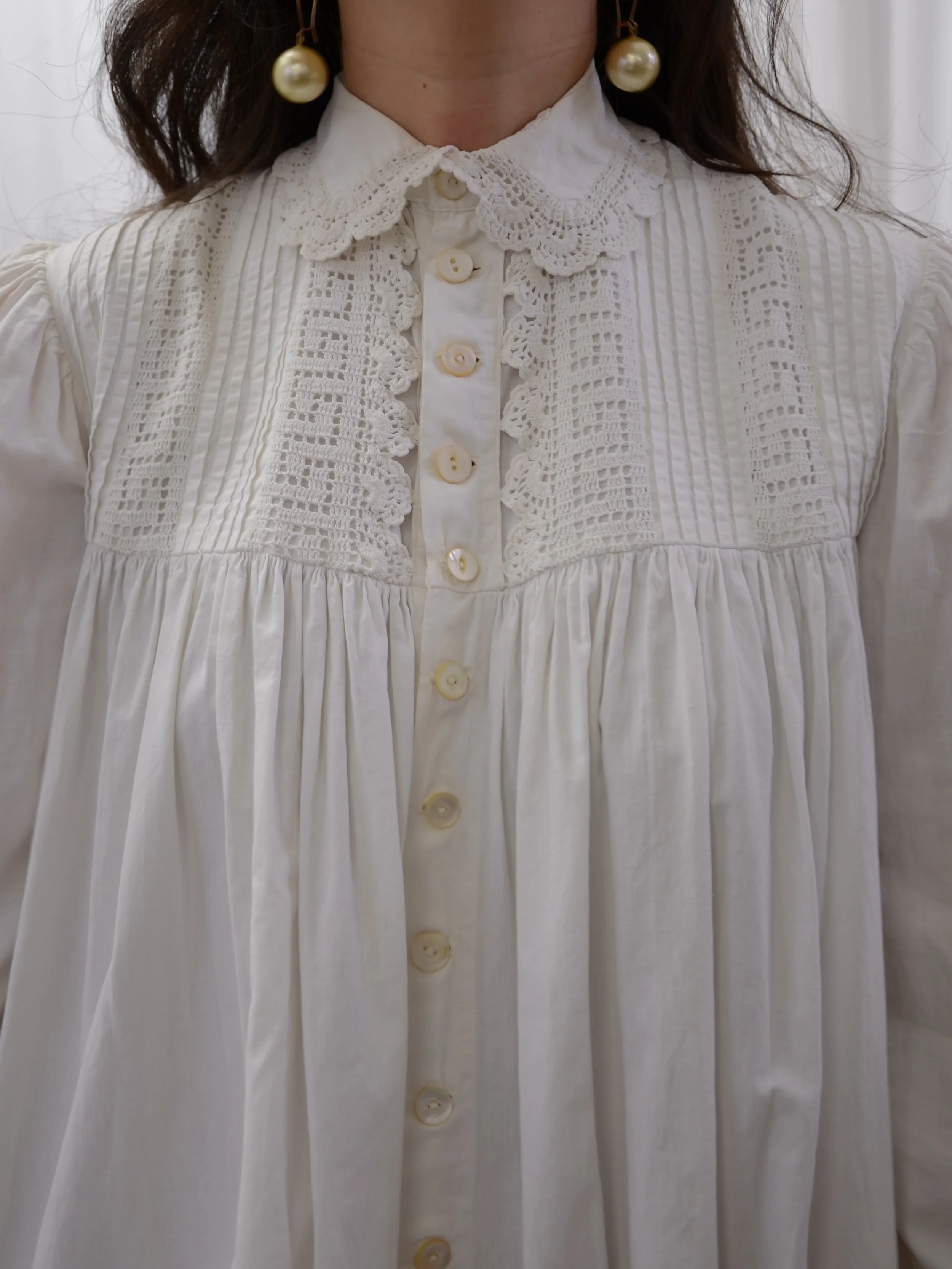 Close-up of the antique white dress's scalloped lace collar, Greek key lace yoke and shell buttons.
