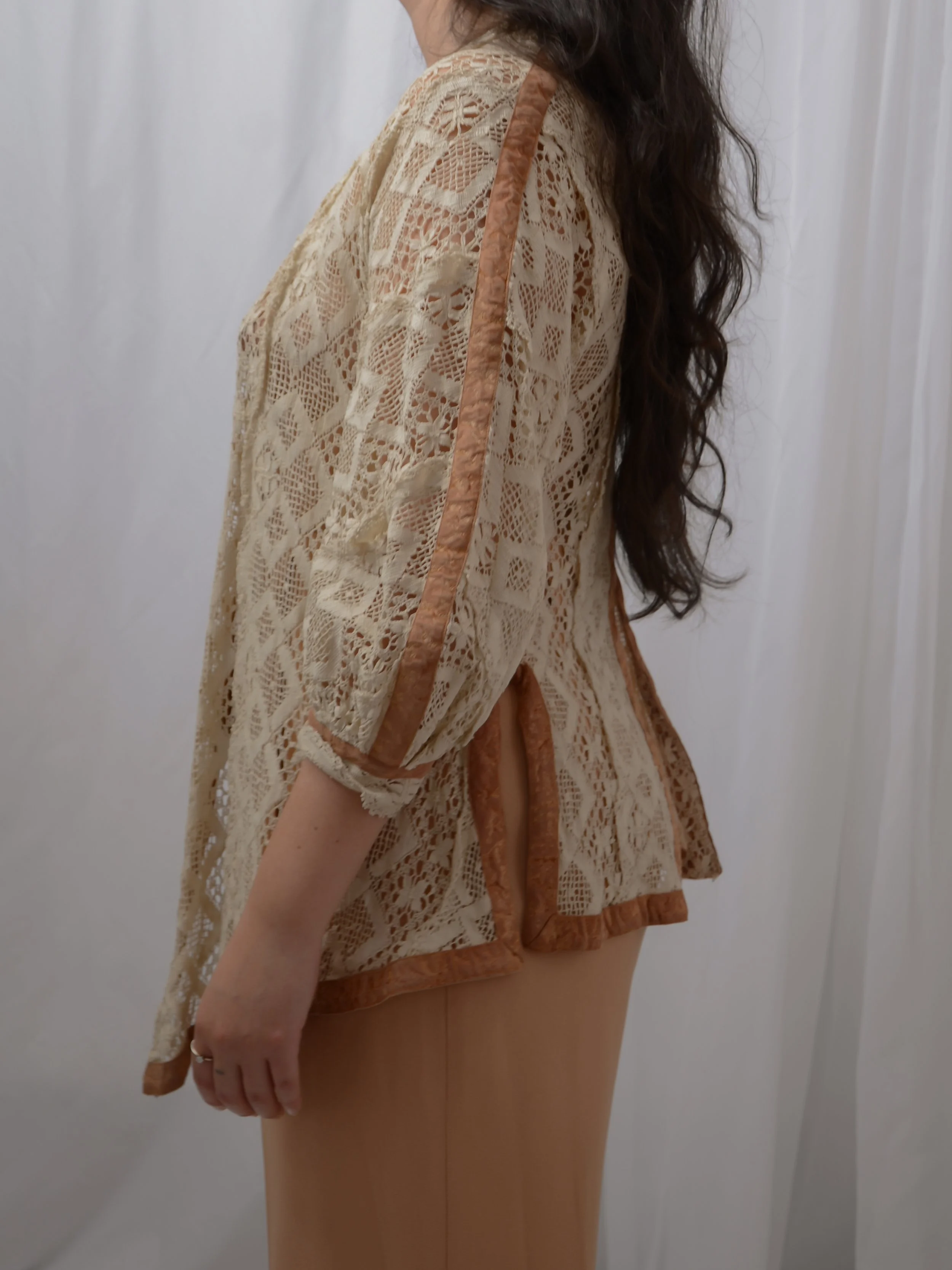 Side view of the Edwardian ecru lace jacket on a model, showing velvet-trimmed sleeve seams and side slit.