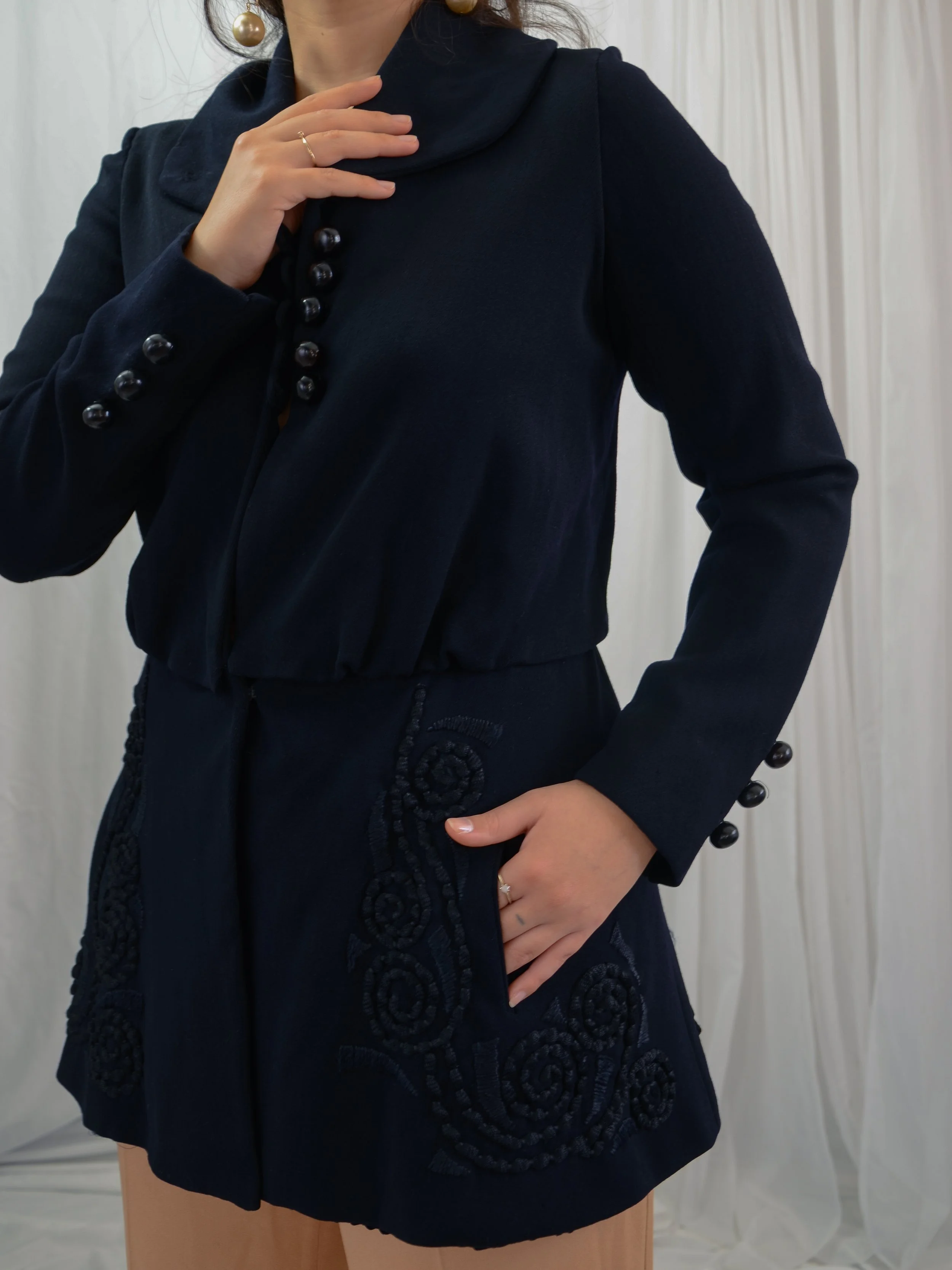 Edwardian navy wool walking jacket on a model with hand in pocket, showing the wide collar and button cuffs.
