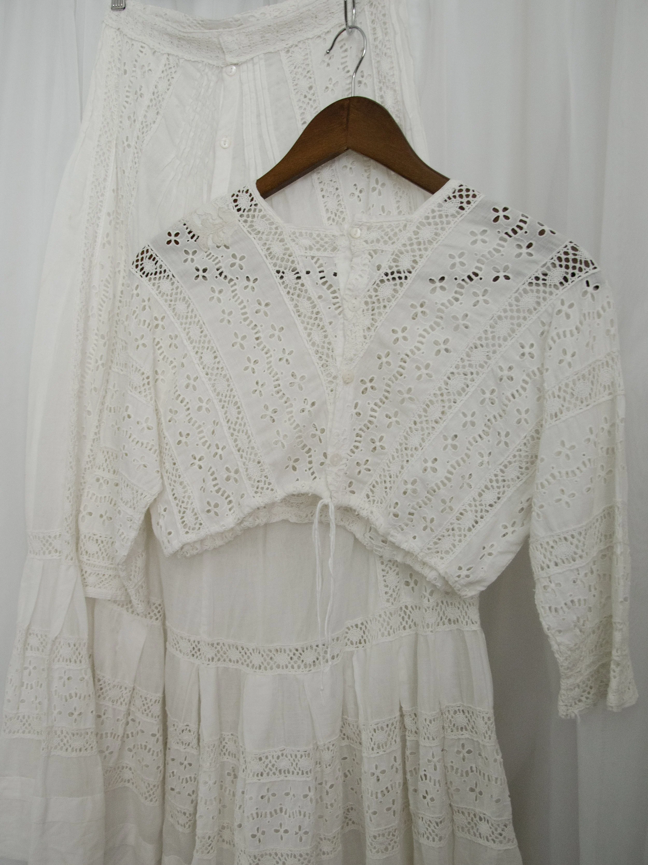 Edwardian white eyelet cropped top on a hanger, back view showing the back buttons.
