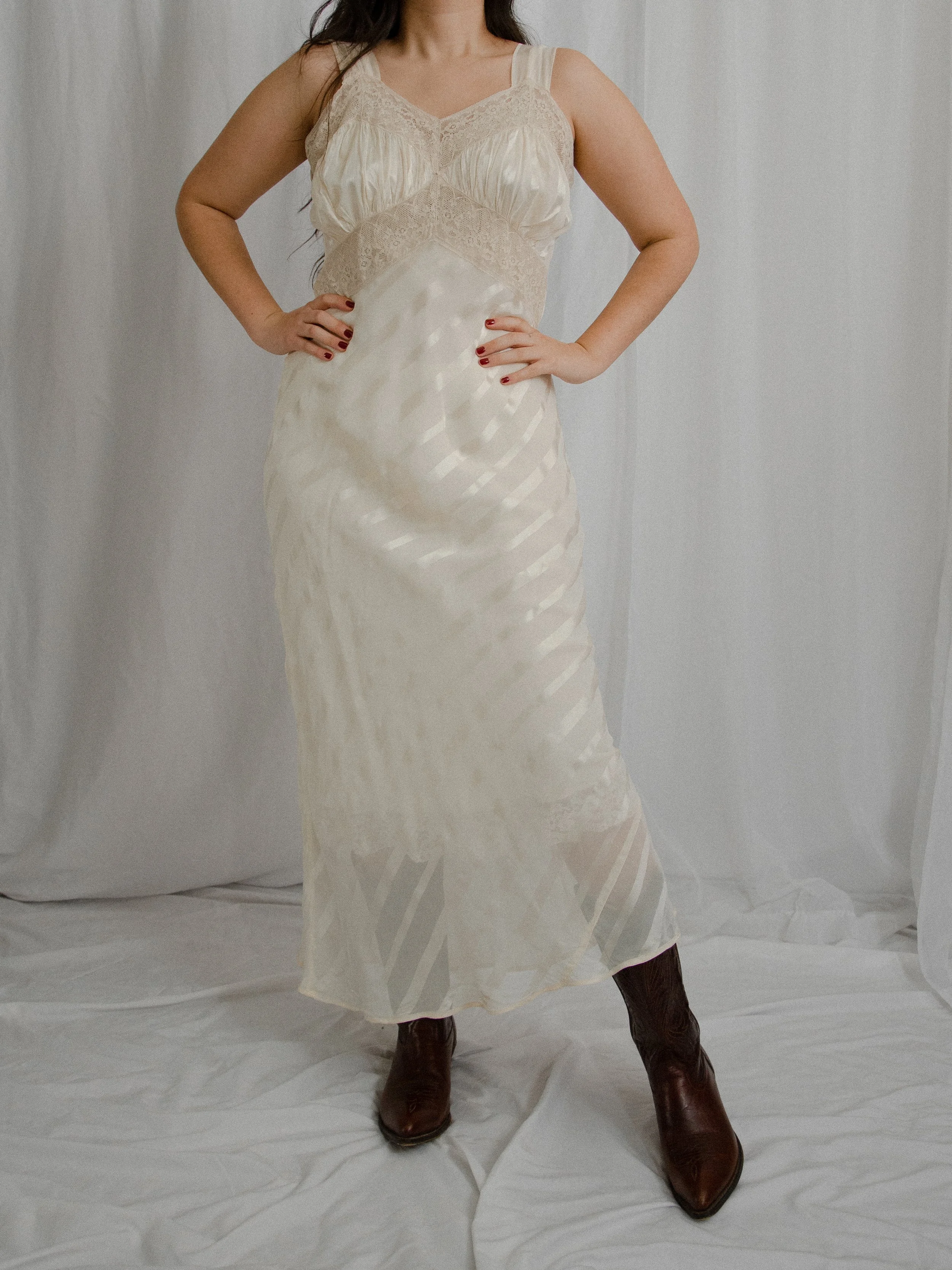Front view of the 1940s ivory striped slip dress on a model posing with hands on hips.