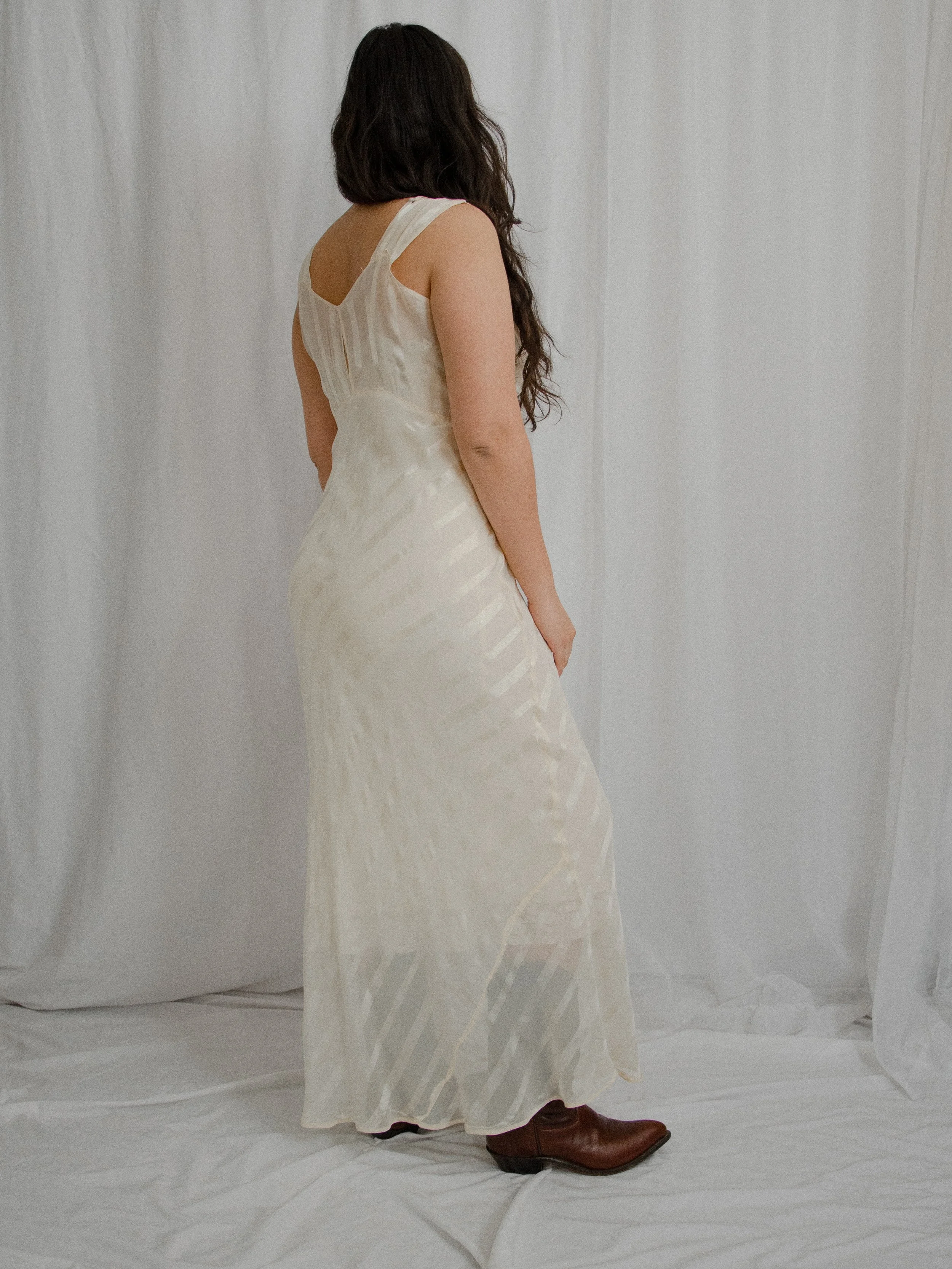 Back view of the 1940s ivory bias-cut slip dress on a model, showing the scooped back and long skirt.