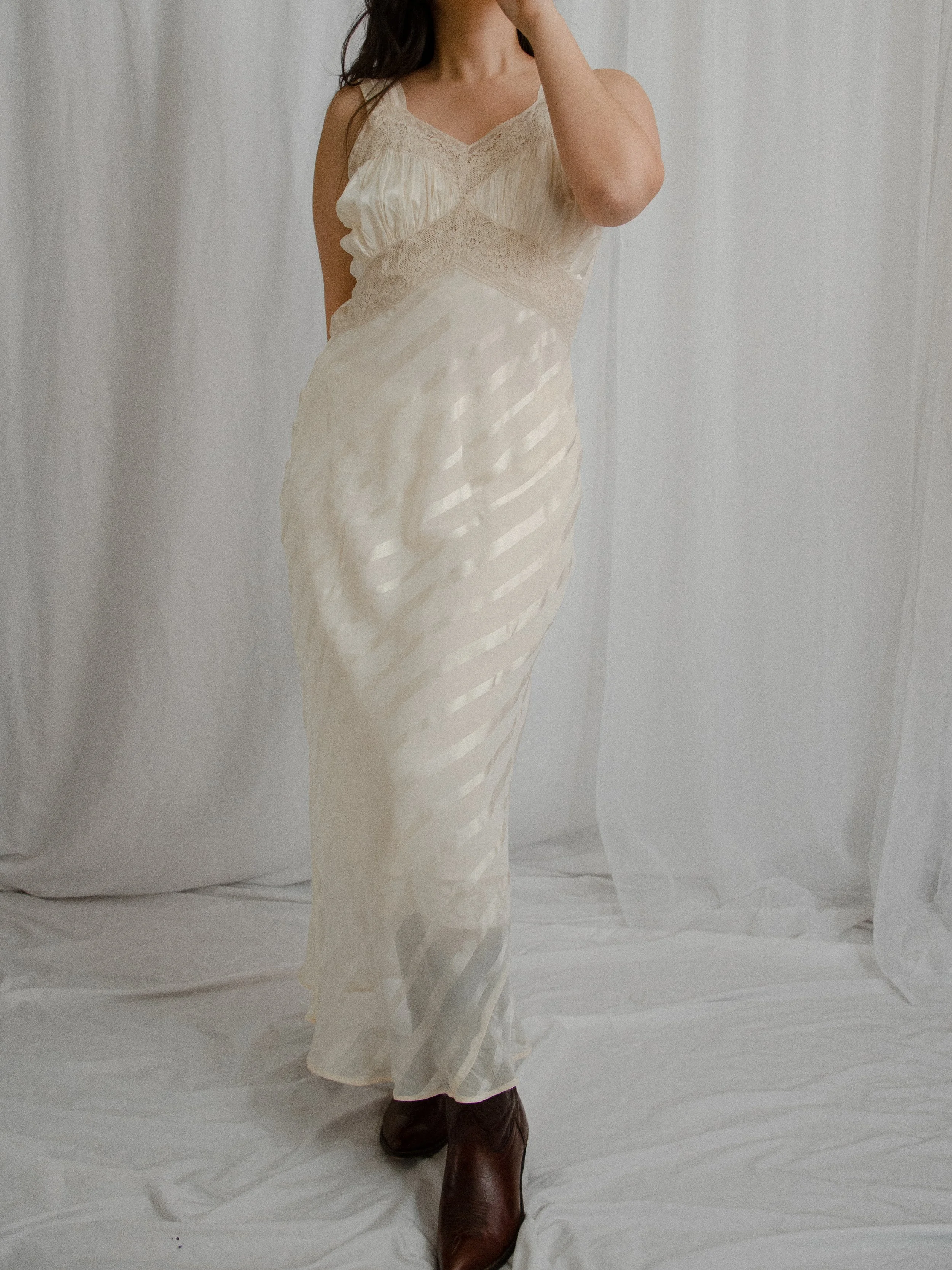 1940s ivory bias-cut slip dress with diagonal satin stripes, worn full length on a model with brown boots.