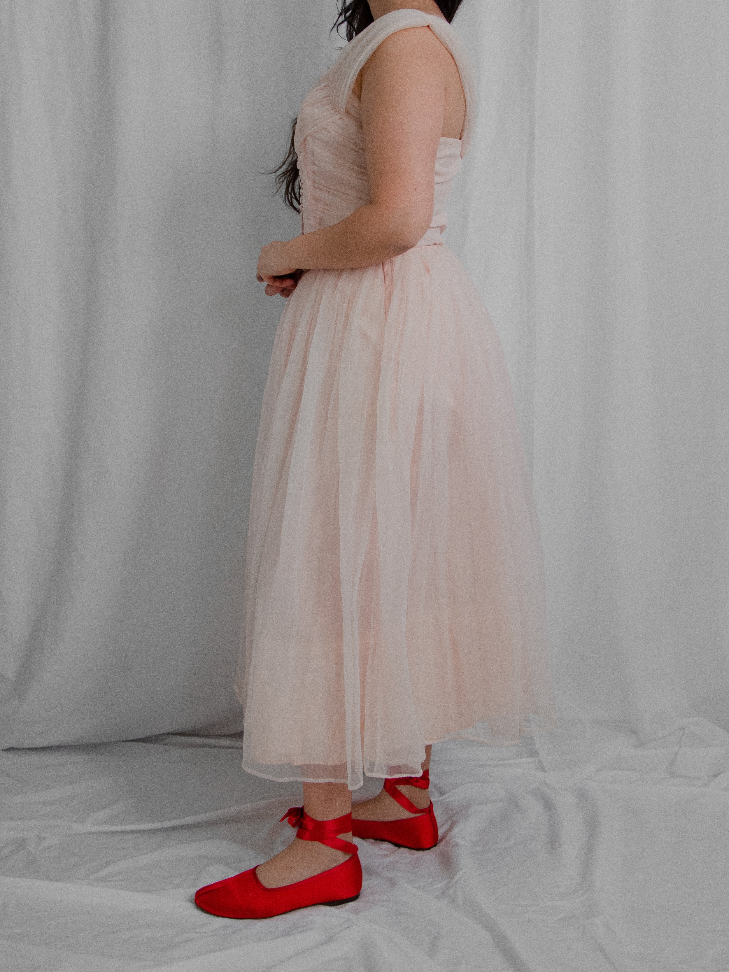 Side view of the 1950s pink nylon ballerina dress on a model, showing the tea-length skirt.