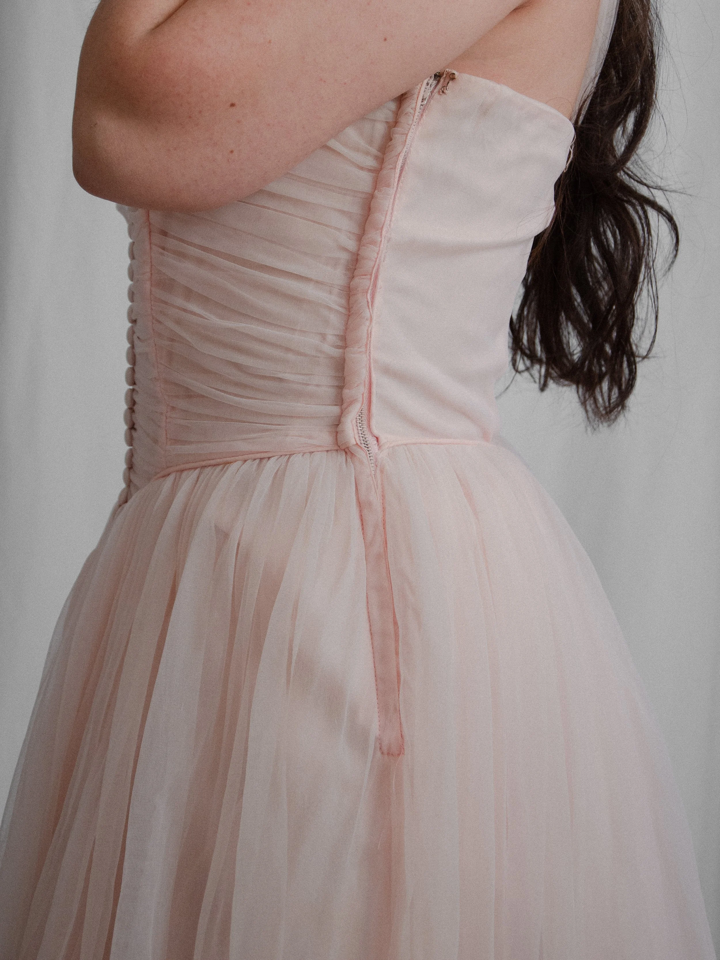 Side detail of the 1950s pink ballerina dress on a model, showing the ruched bodice and zipper.