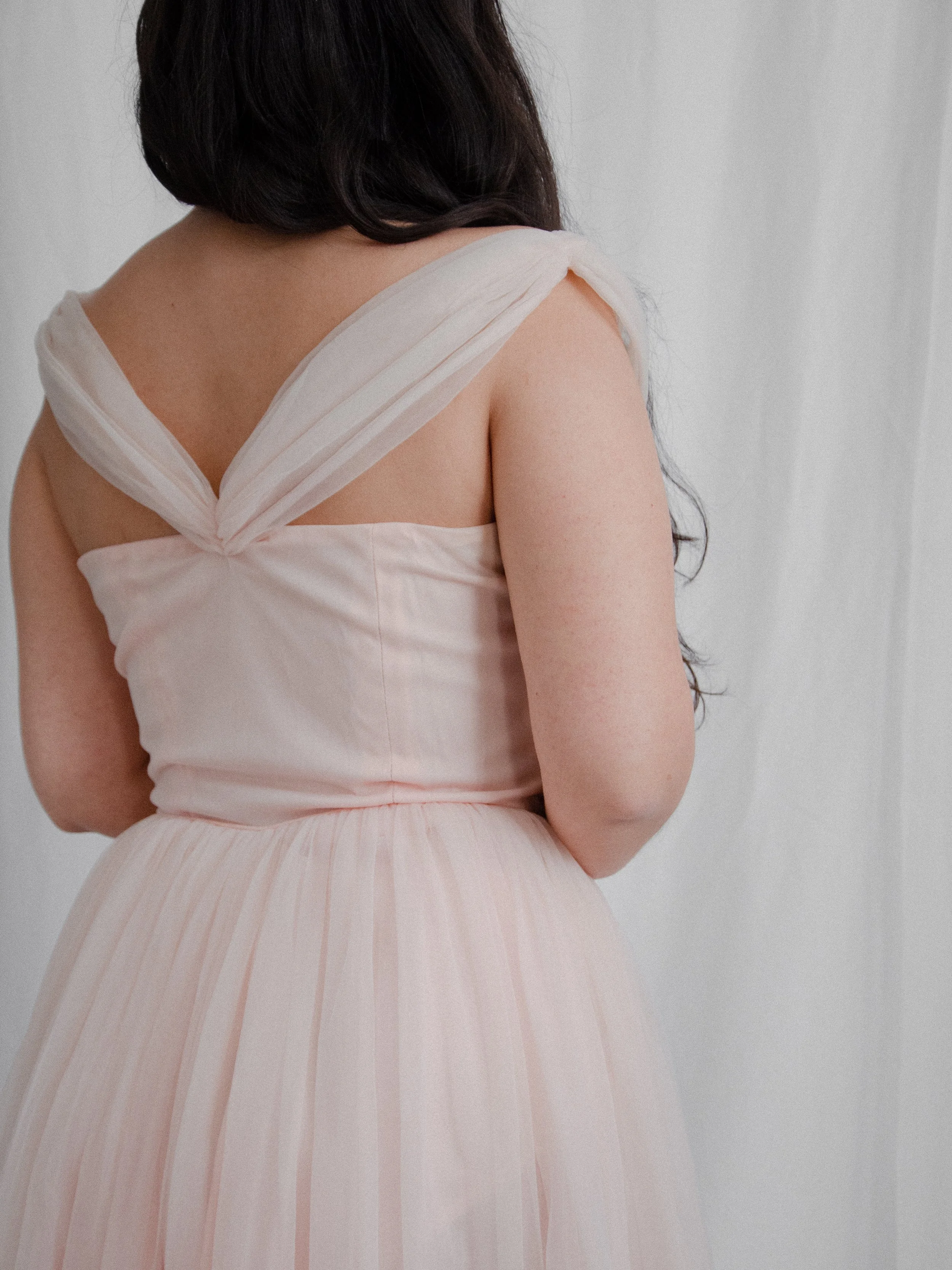 Back view of the 1950s pink ballerina dress bodice on a model, showing the crisscross ruched straps.