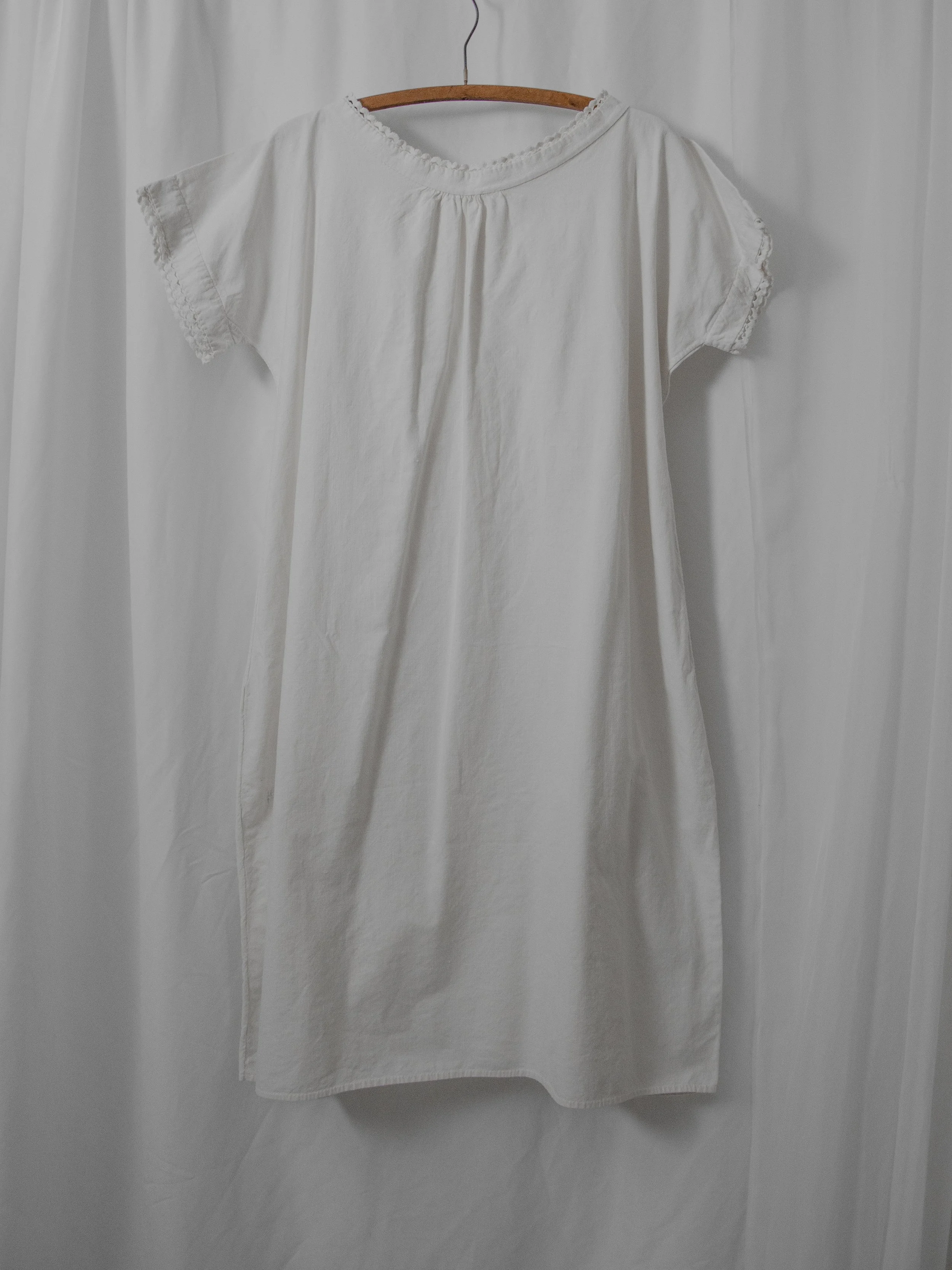 Victorian white cotton smock dress on a wooden hanger, full front view with short sleeves.
