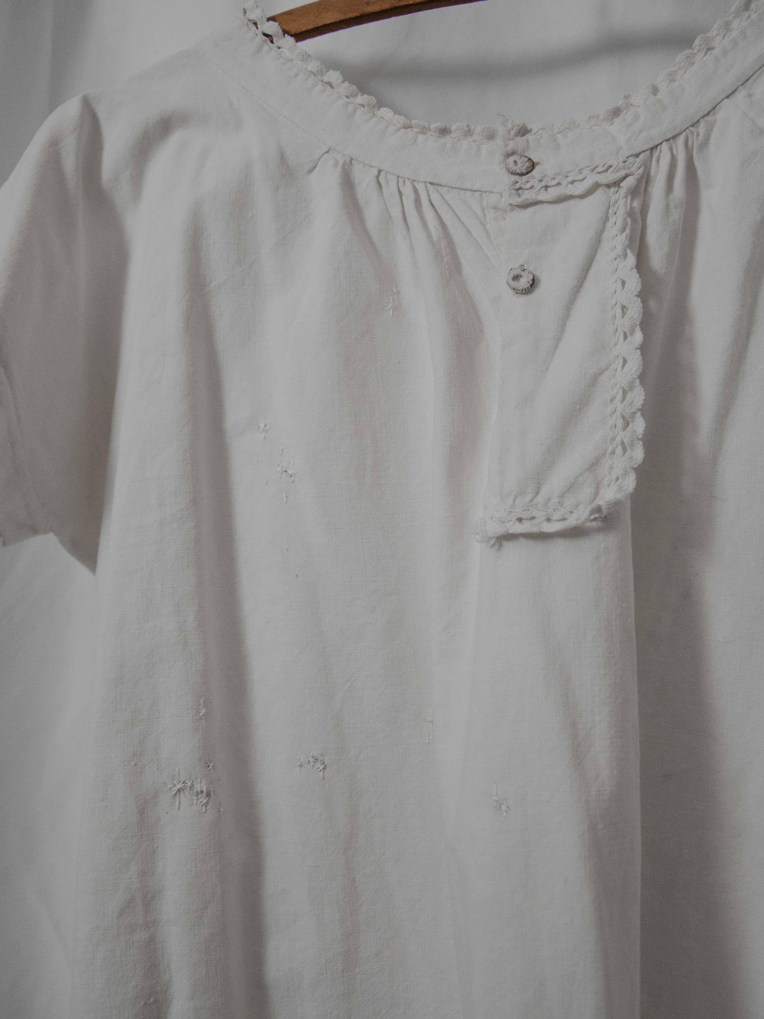 Close-up of the Victorian smock dress placket on a hanger, showing metal buttons and small embroidered stars.