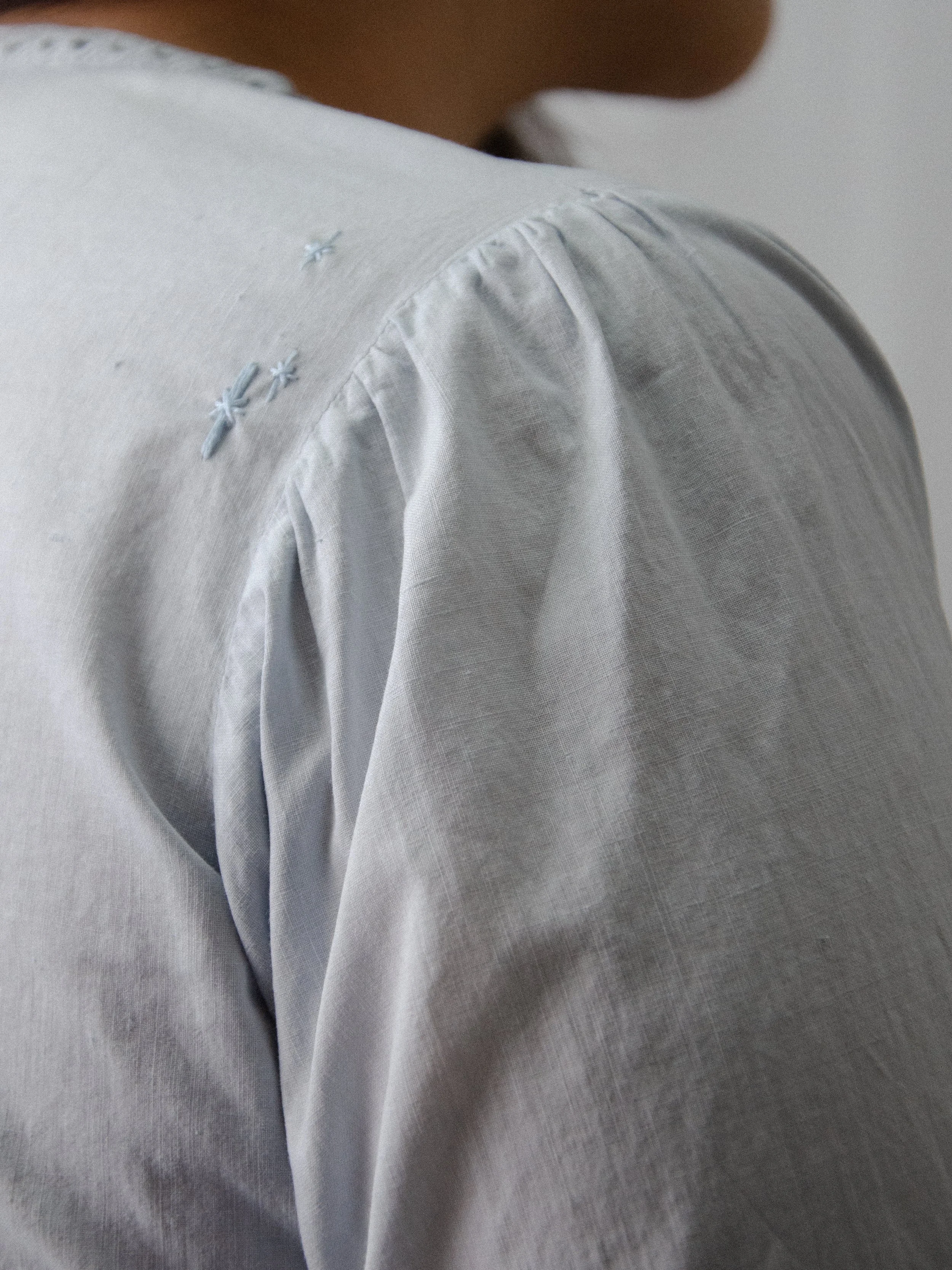 Close-up of the light blue antique cotton top's shoulder, showing hand-embroidered twinkle stars.