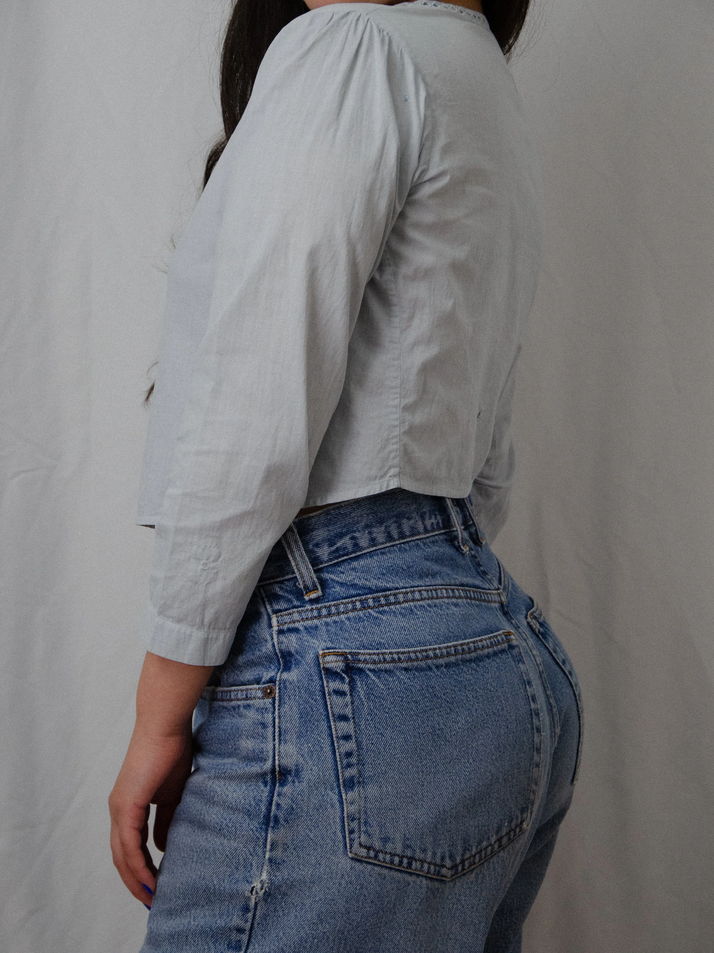 Side view of the light blue antique cotton top on a model, showing the cropped length and sleeve.