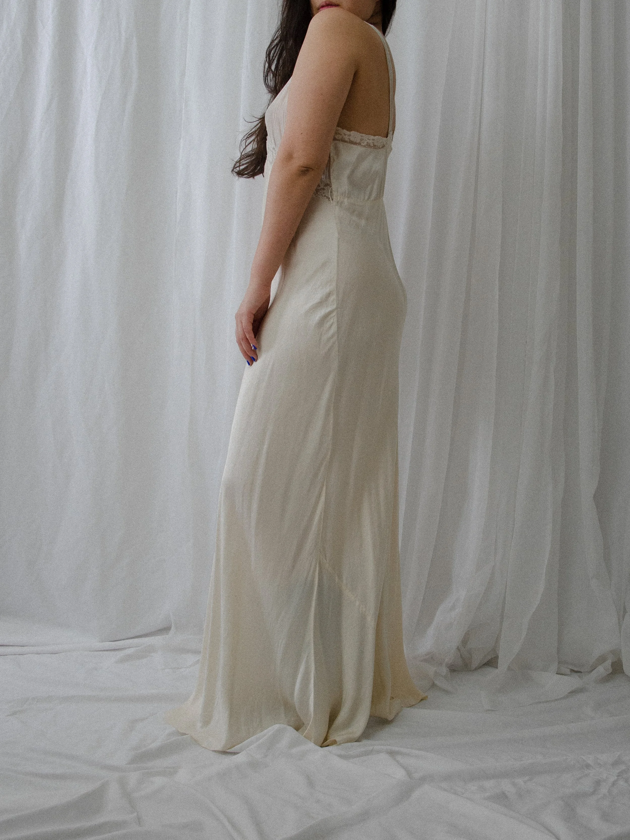 Side view of the 1930s ivory silk slip dress on a model, showing the bias-cut drape.