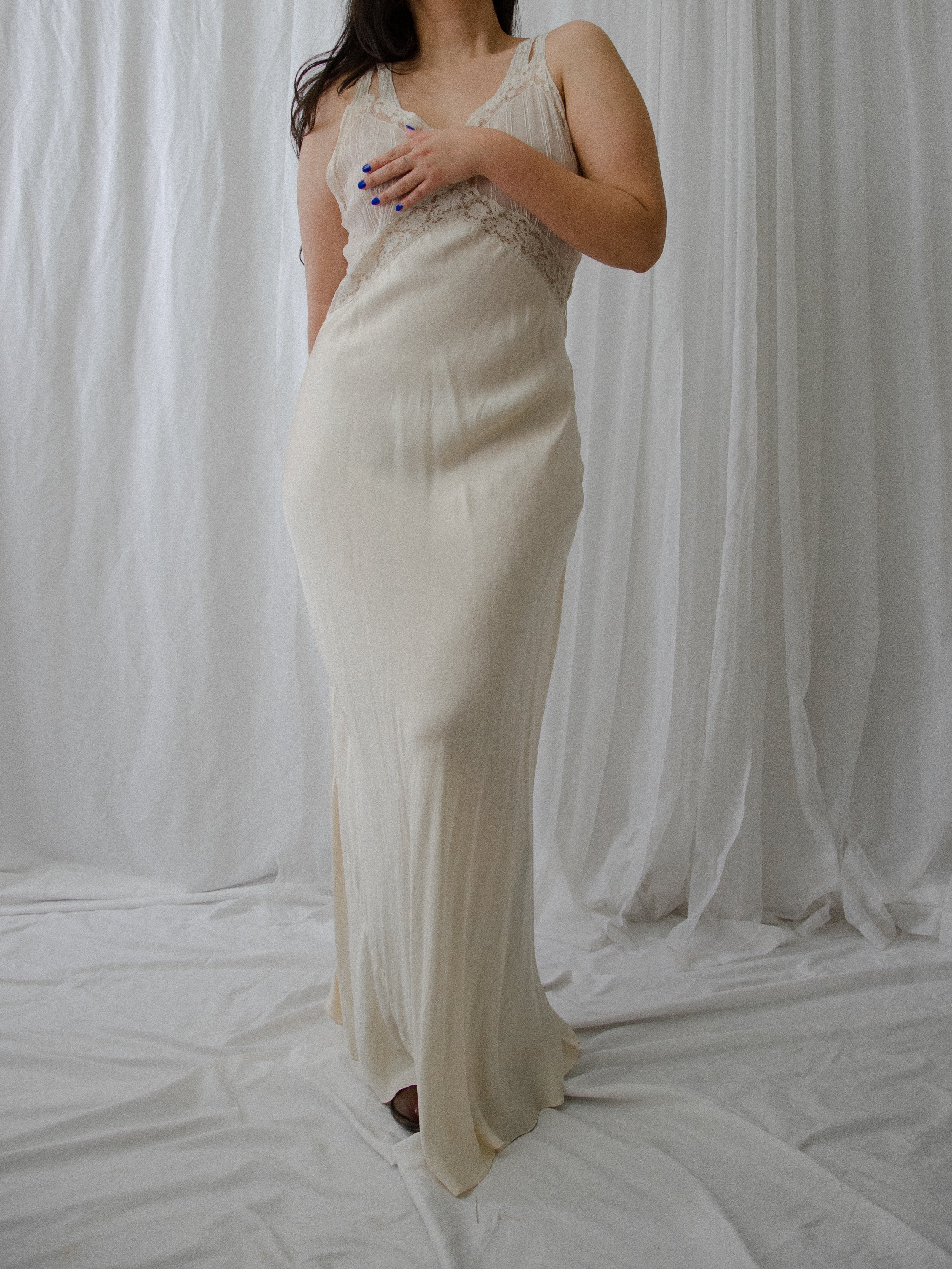 1930s ivory silk slip dress on a model, three-quarter view showing the lace bodice and full-length skirt.