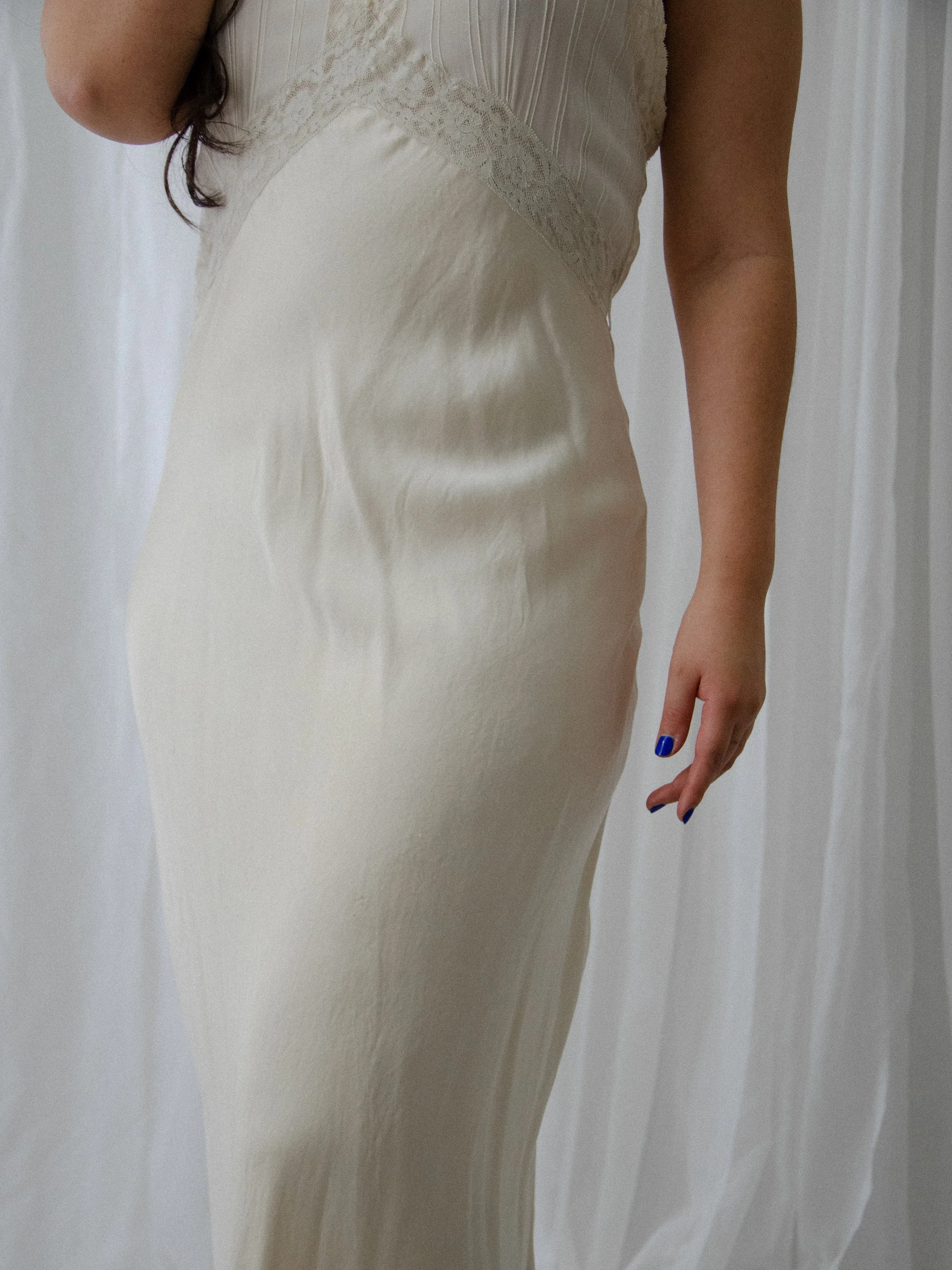 Detail of the 1930s ivory silk slip dress at the hip on a model, showing the soft silk sheen.