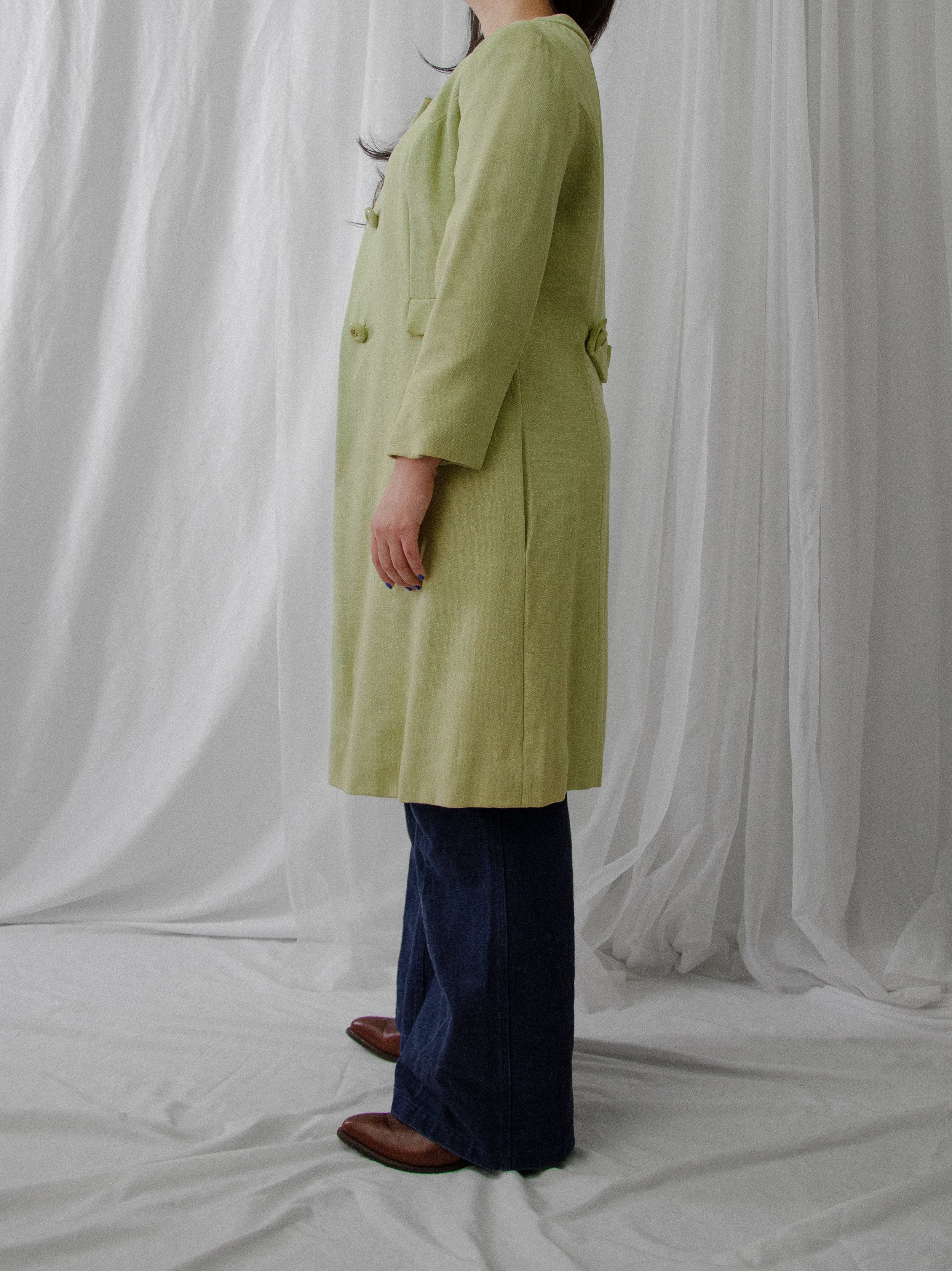 Side view of the 1950s pistachio green linen coat on a model, showing its knee length.