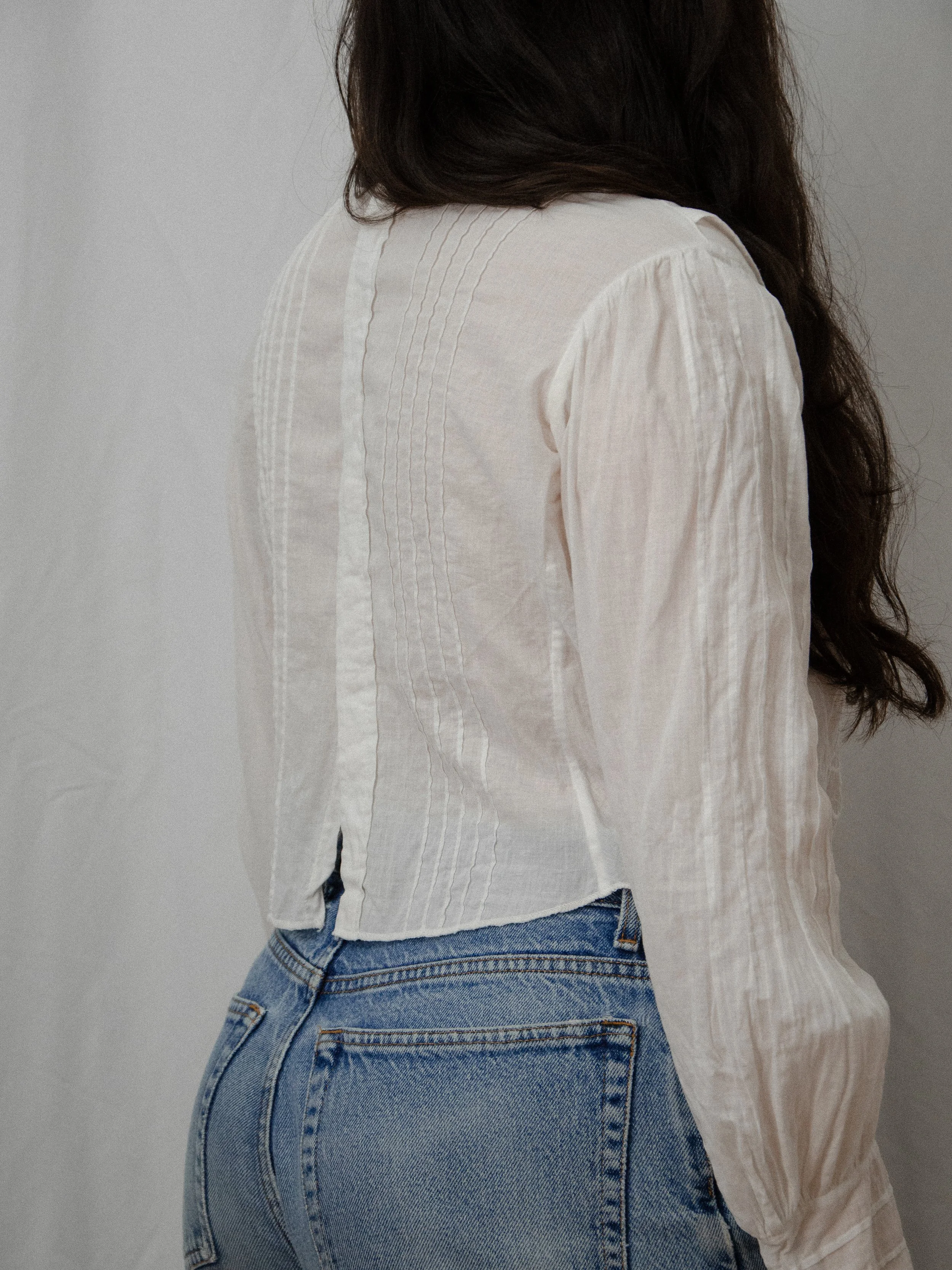 Back view of the Edwardian white cotton top on a model, showing the button placket and pintucked panels.