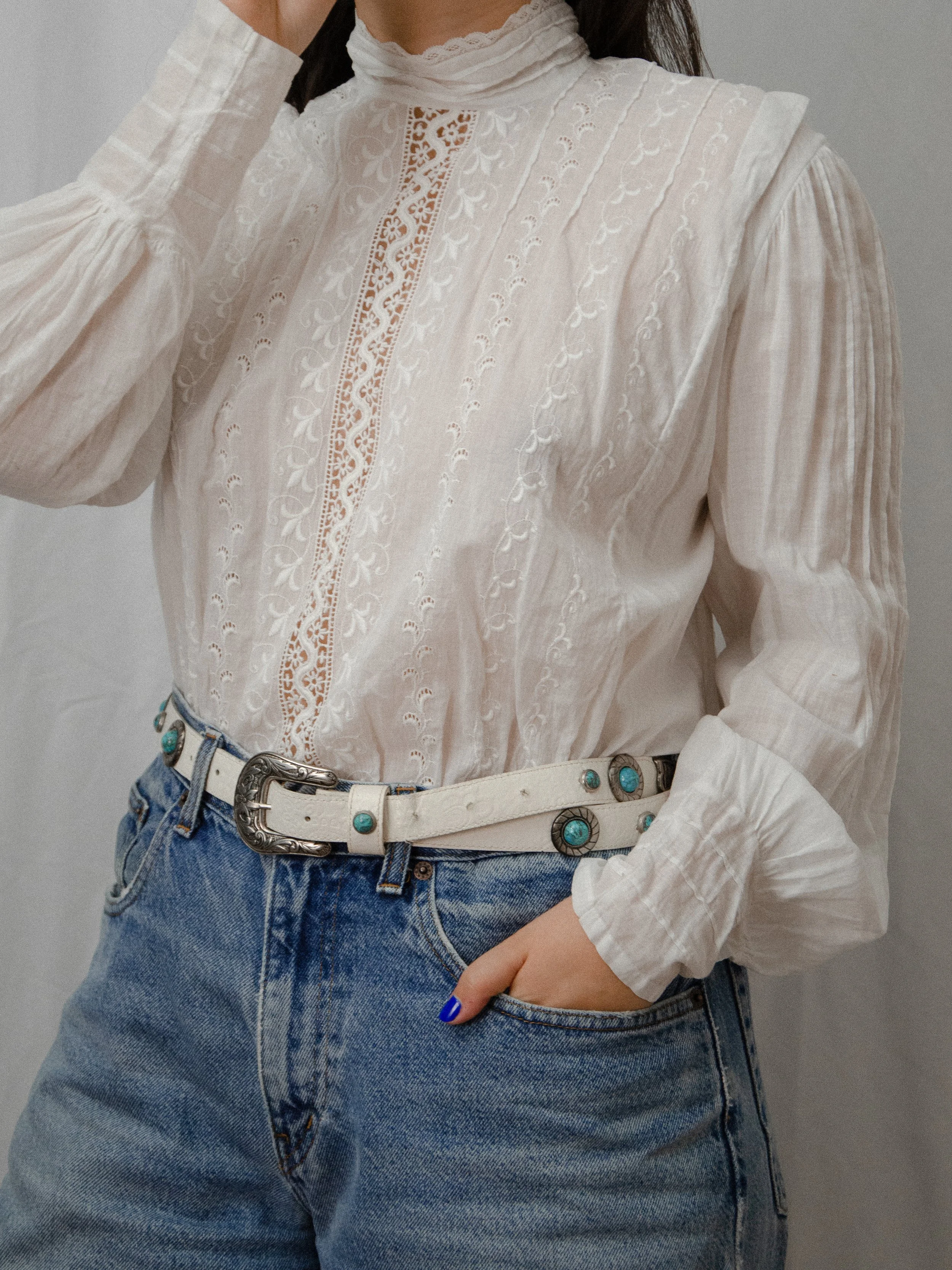 Edwardian white cotton mock neck top on a model with one arm raised, showing the full puffed sleeve.