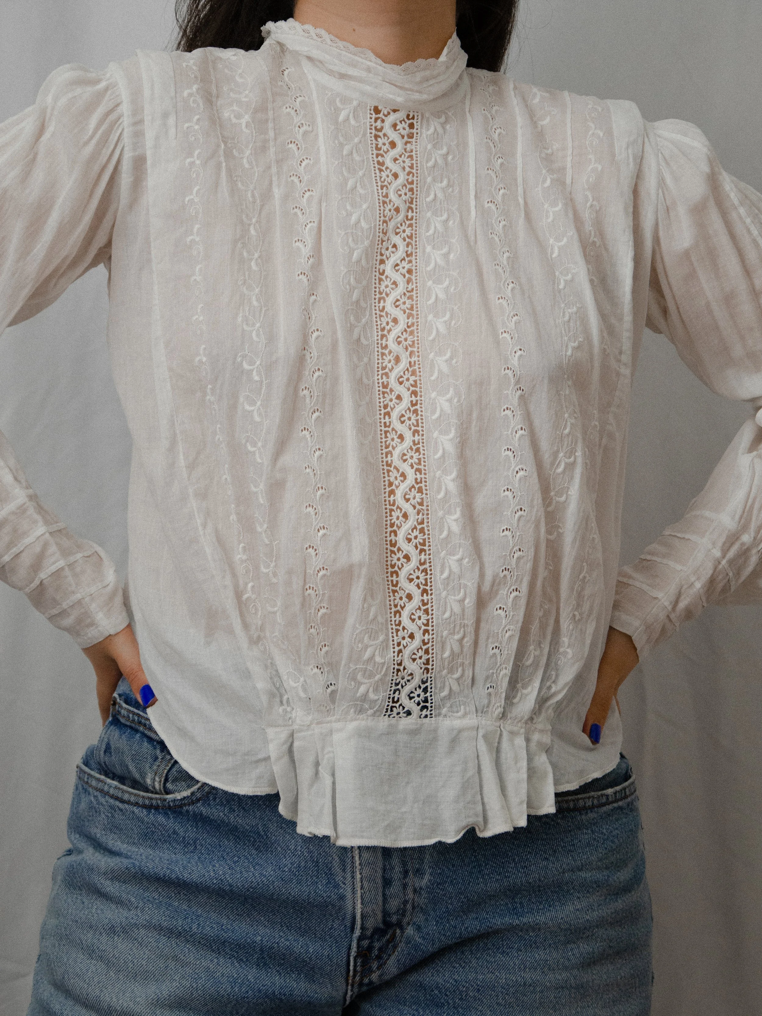 Front view of the 1910s white cotton mock neck top worn untucked, showing the gathered peplum waist.