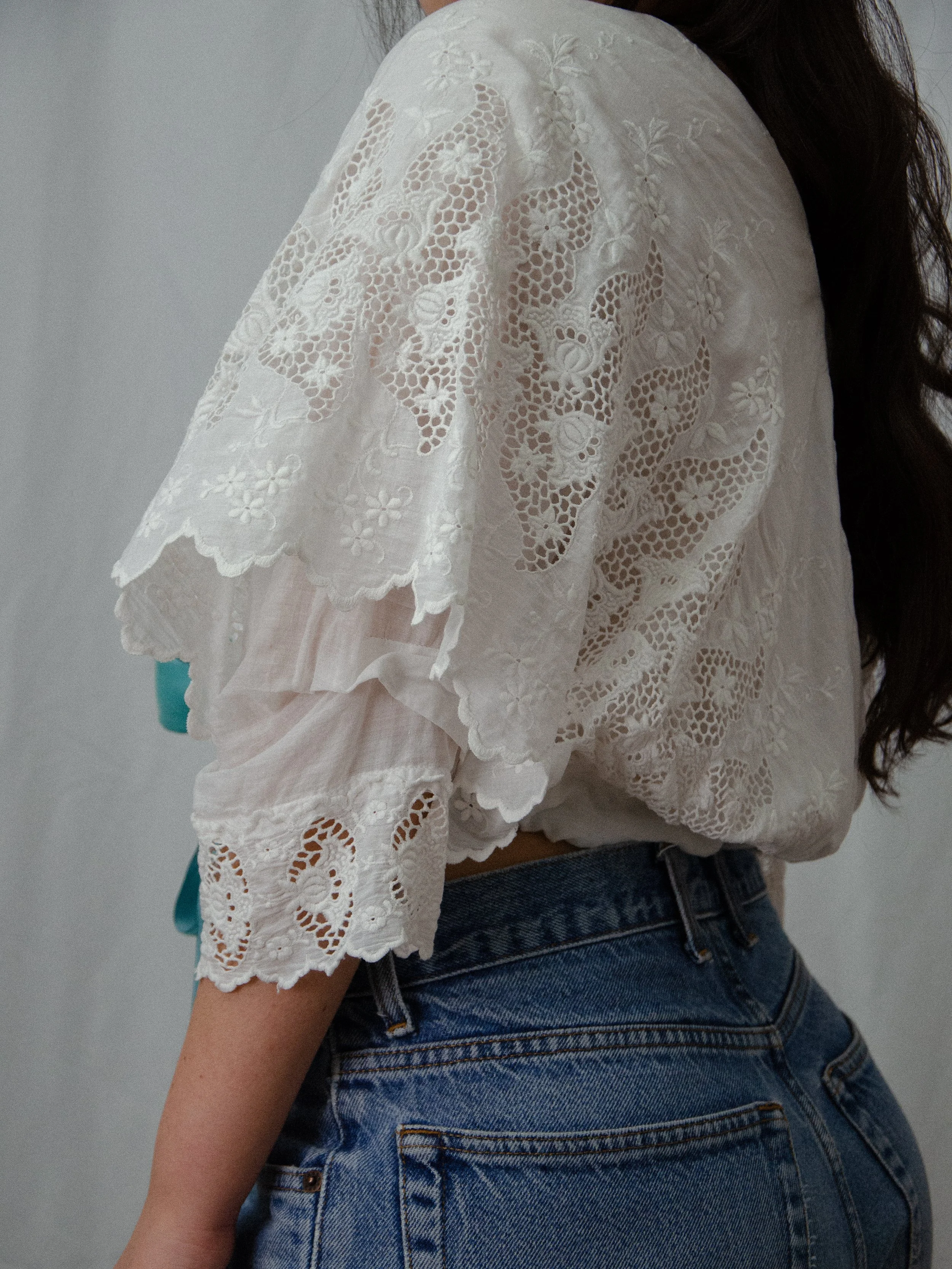 Side view of the antique cotton wrap blouse on a model, showing the scalloped lace sleeve layers.